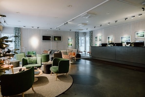 A modern lobby with green seating, a reception desk, and framed artwork on the walls.