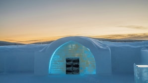 An igloo with a brick entrance and a snowy landscape in the background.
