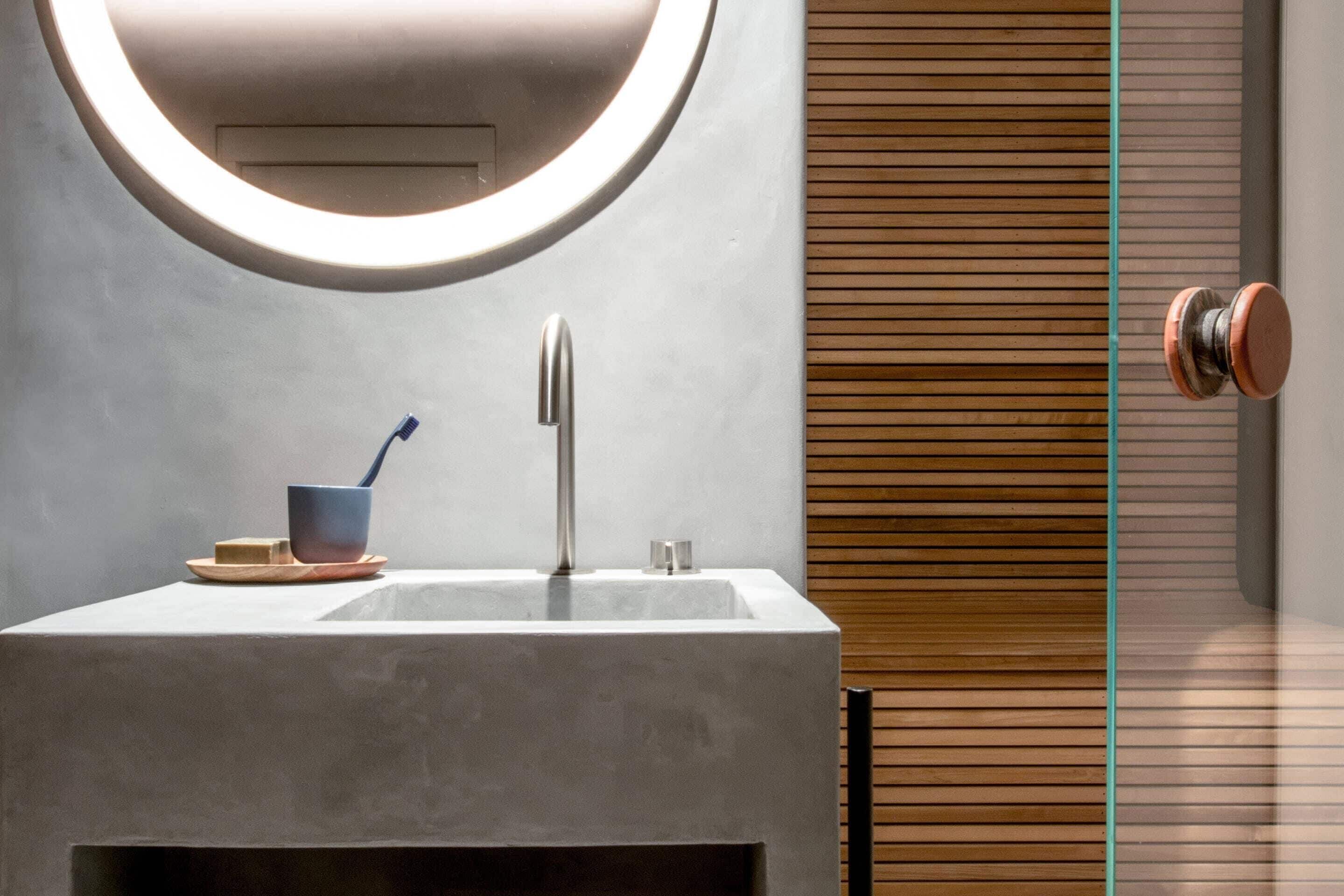 A bathroom with a modern sink, a mirror, and a wooden panel wall.