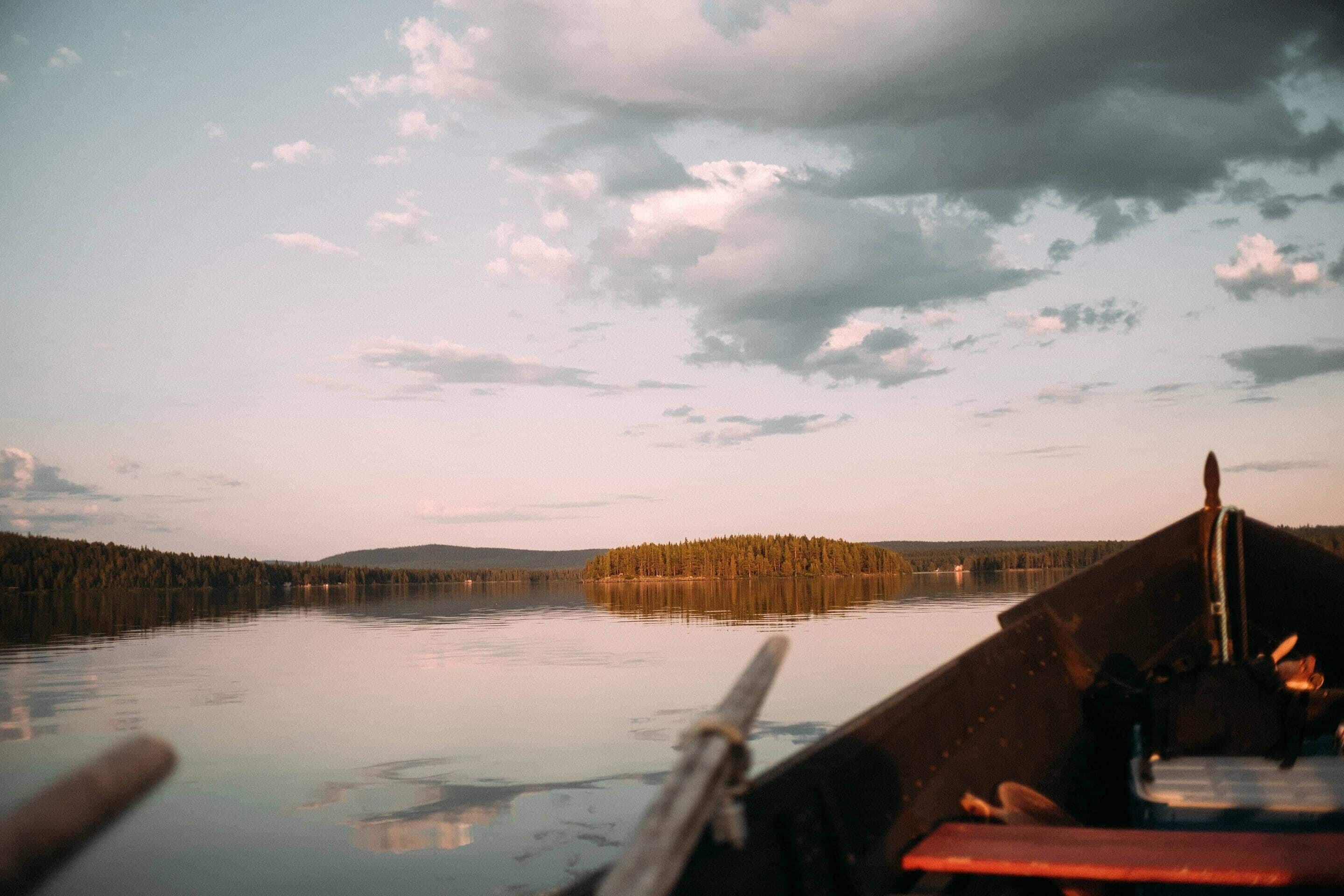 Un lago tranquilo con una isla boscosa a lo lejos, visto desde un bote.