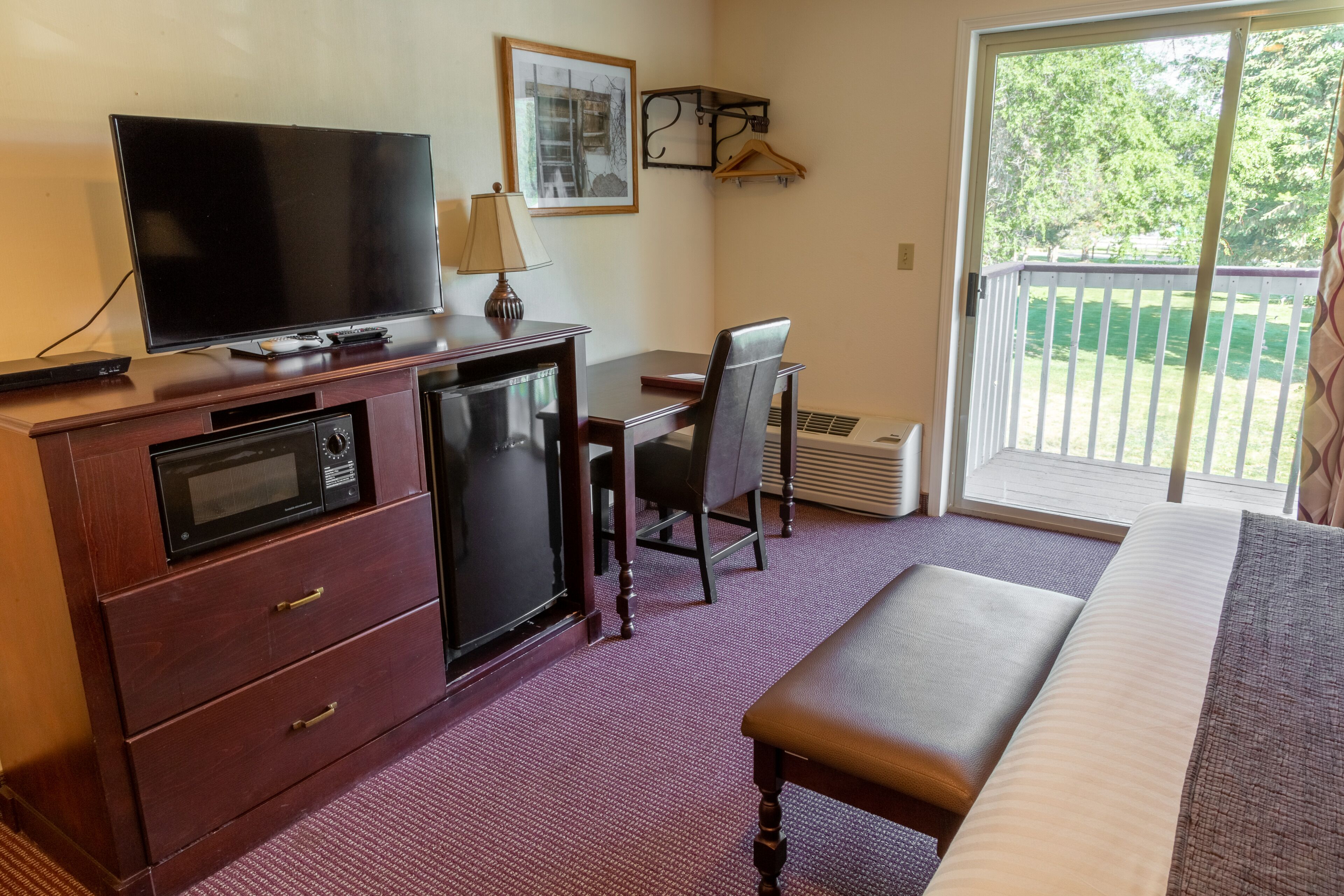A hotel room with a TV, desk, chair, and a bed.