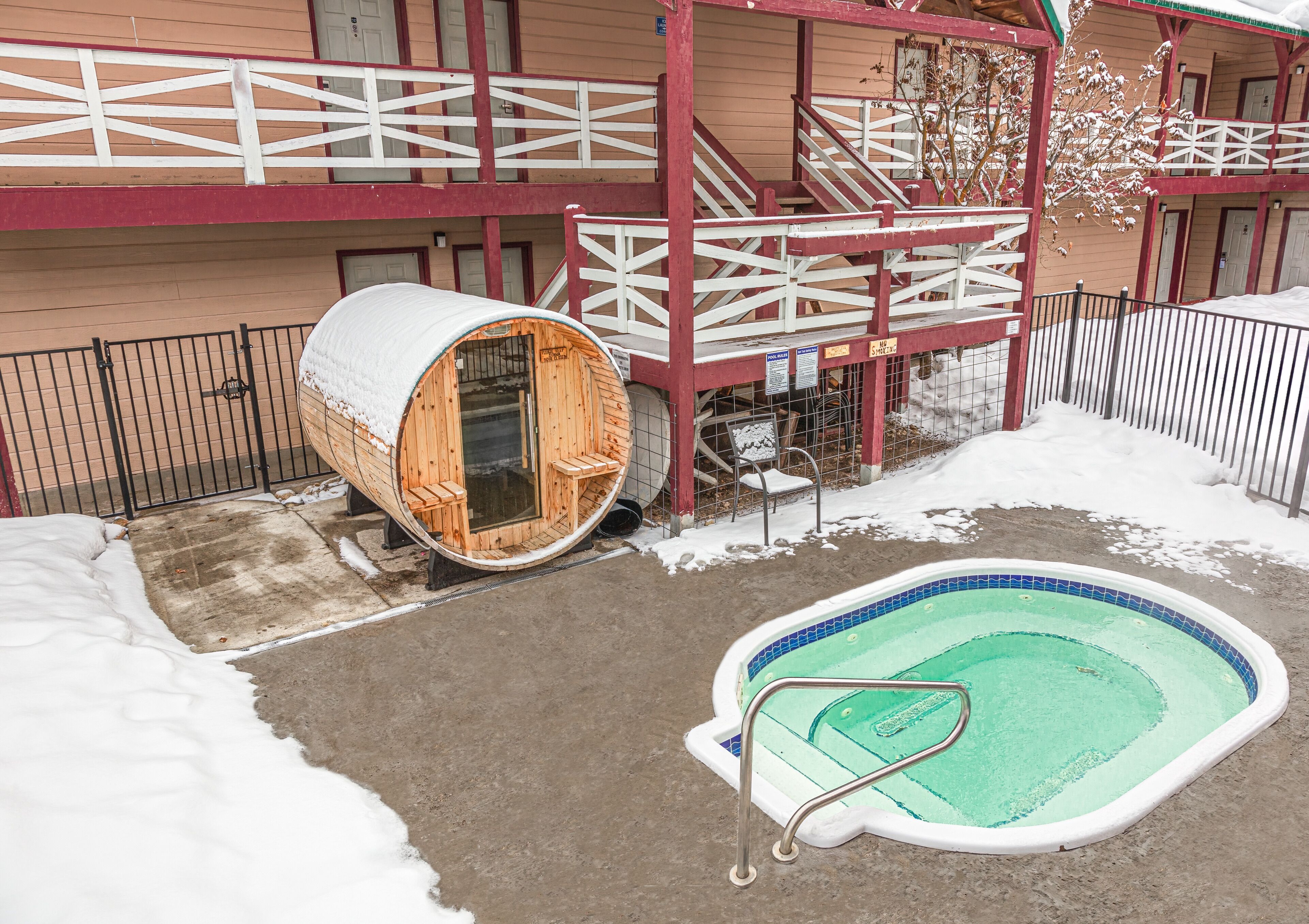 A wooden sauna, a pool, and a building with a red and white exterior.
