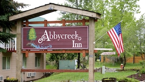 A sign for Abbyg Creek Inn with a wooden structure, a flag, and a 'VACANCY' sign.