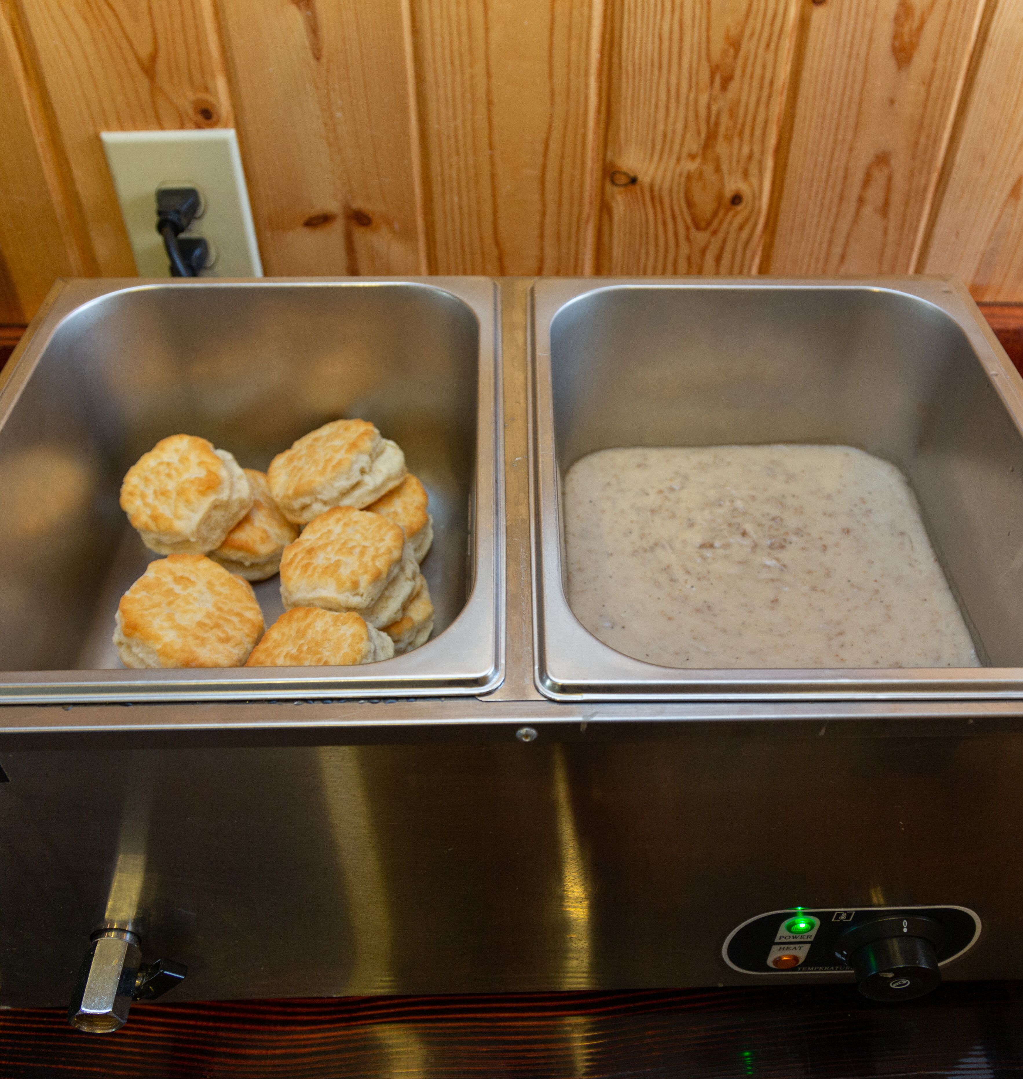 Un electrodoméstico de acero inoxidable con dos compartimentos; uno contiene galletas y el otro está vacío.