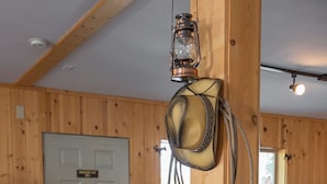A rustic interior with wooden walls, a wooden door labeled "Emergency Exit," a leather saddle, and a lantern hanging from the ceiling.