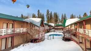 A hotel with multiple balconies, a pool, and snow-covered roofs.