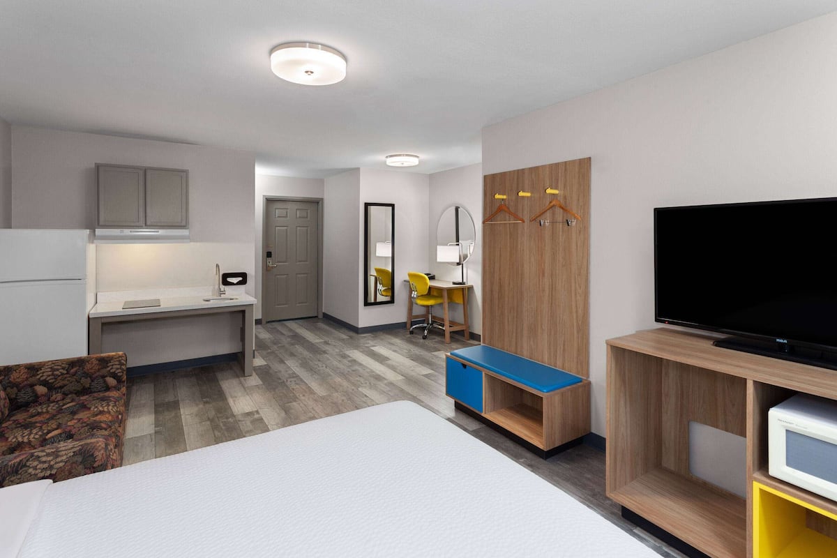 A hotel room with a bed, a desk, a chair, a TV, and a wardrobe.