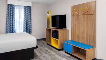 Une chambre d’hôtel avec un lit, une télévision, une armoire et un banc.