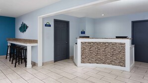 A kitchen with a white countertop, black stools, and a door. - Days Inn & Suites by Wyndham Sellersburg (Sellersburg)