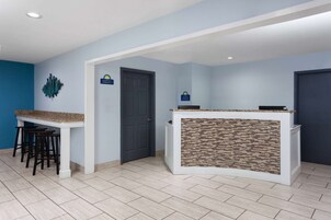 Una cocina con encimera blanca, taburetes negros y una puerta.