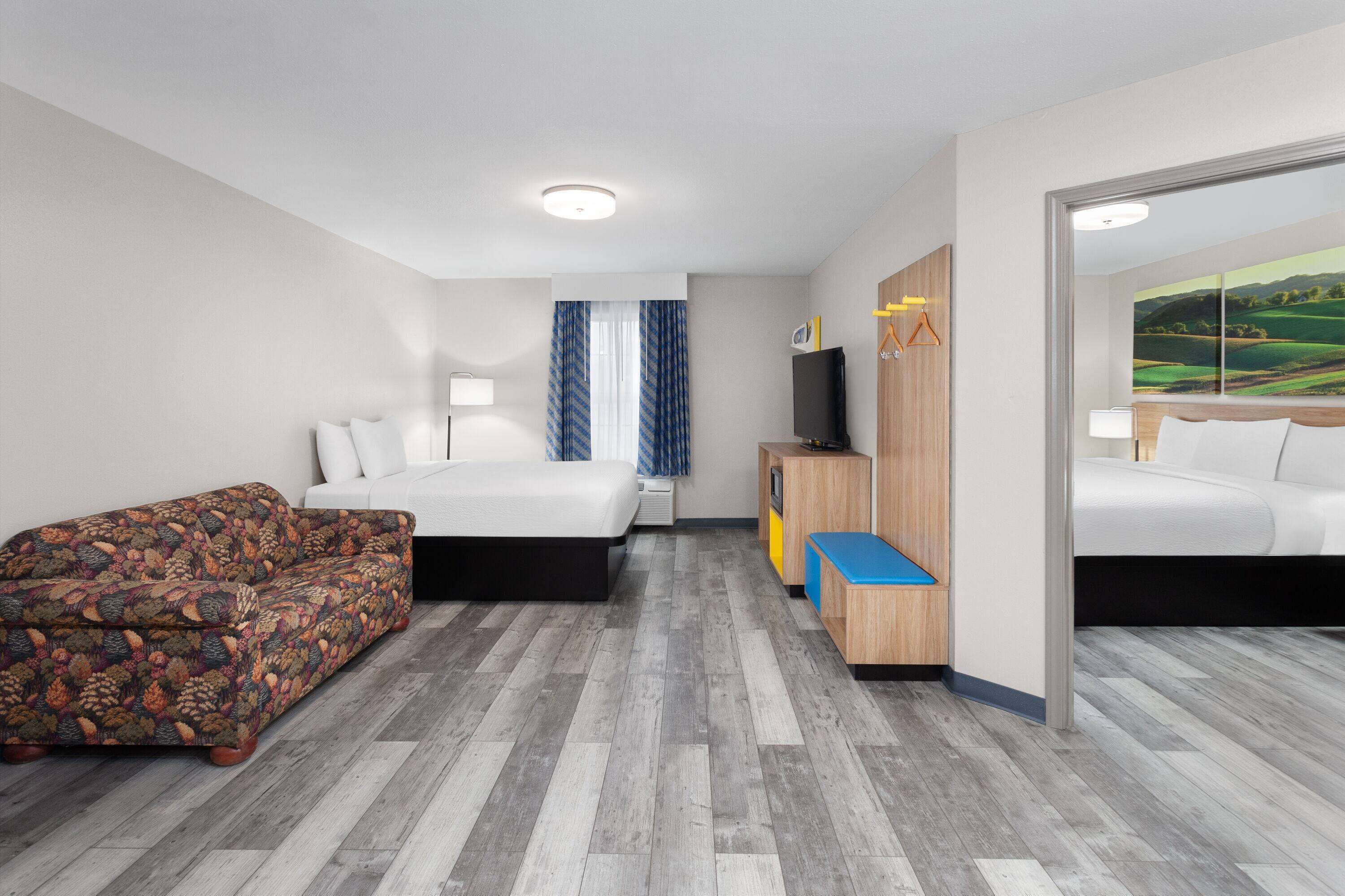 A hotel room with a bed, a sofa, a TV, and a desk.