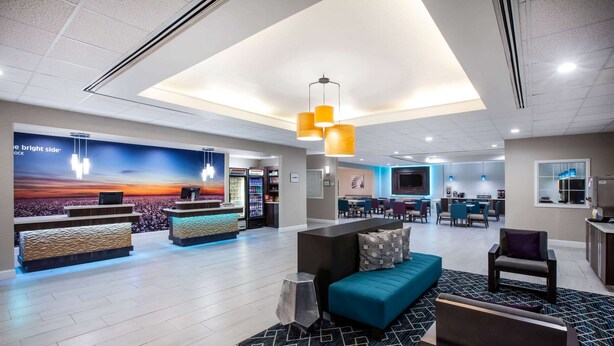 A hotel lobby with a reception desk, seating area, and a large wall mural. - La Quinta Inn & Suites by Wyndham Lubbock North (Lubbock)