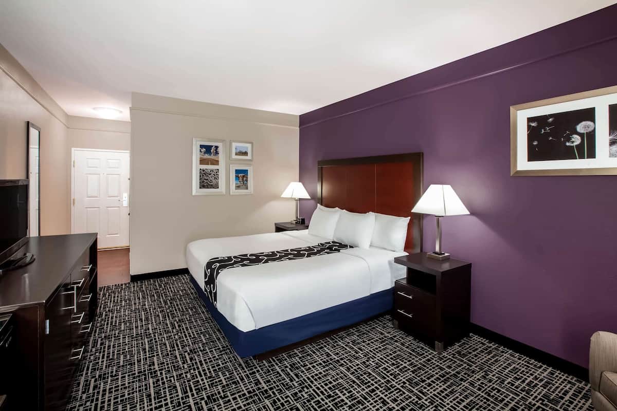 A hotel room with a bed, two bedside tables, a desk, and a TV.