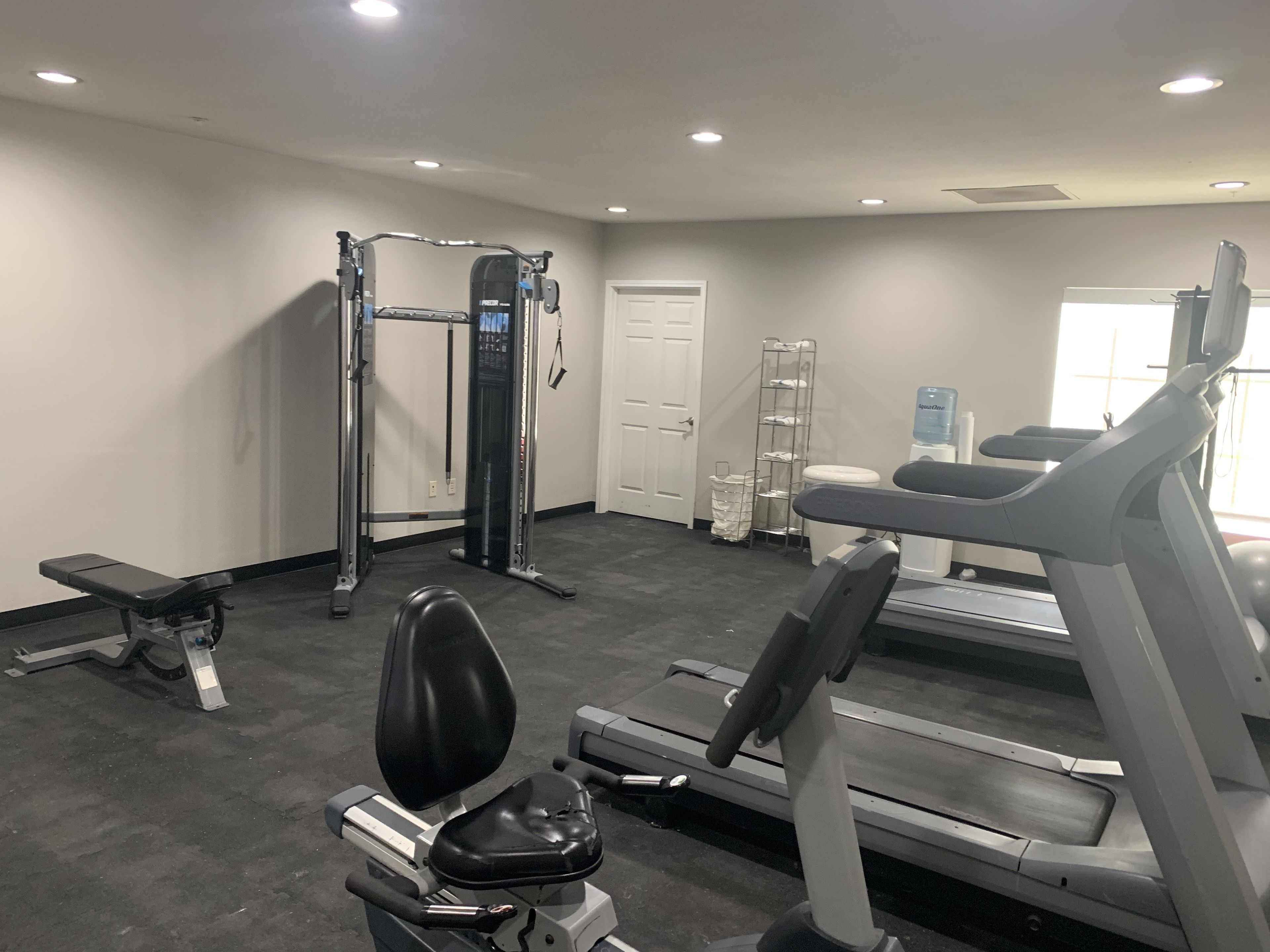 A gym with a treadmill, weight machines, and a bench.