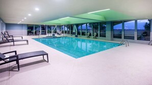 An indoor swimming pool with lounge chairs and a view of the sea through large windows. - La Quinta Inn & Suites by Wyndham Lubbock North (Lubbock)