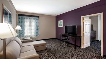 Une chambre d’hôtel avec un canapé, une télévision, un bureau et une moquette à motifs.