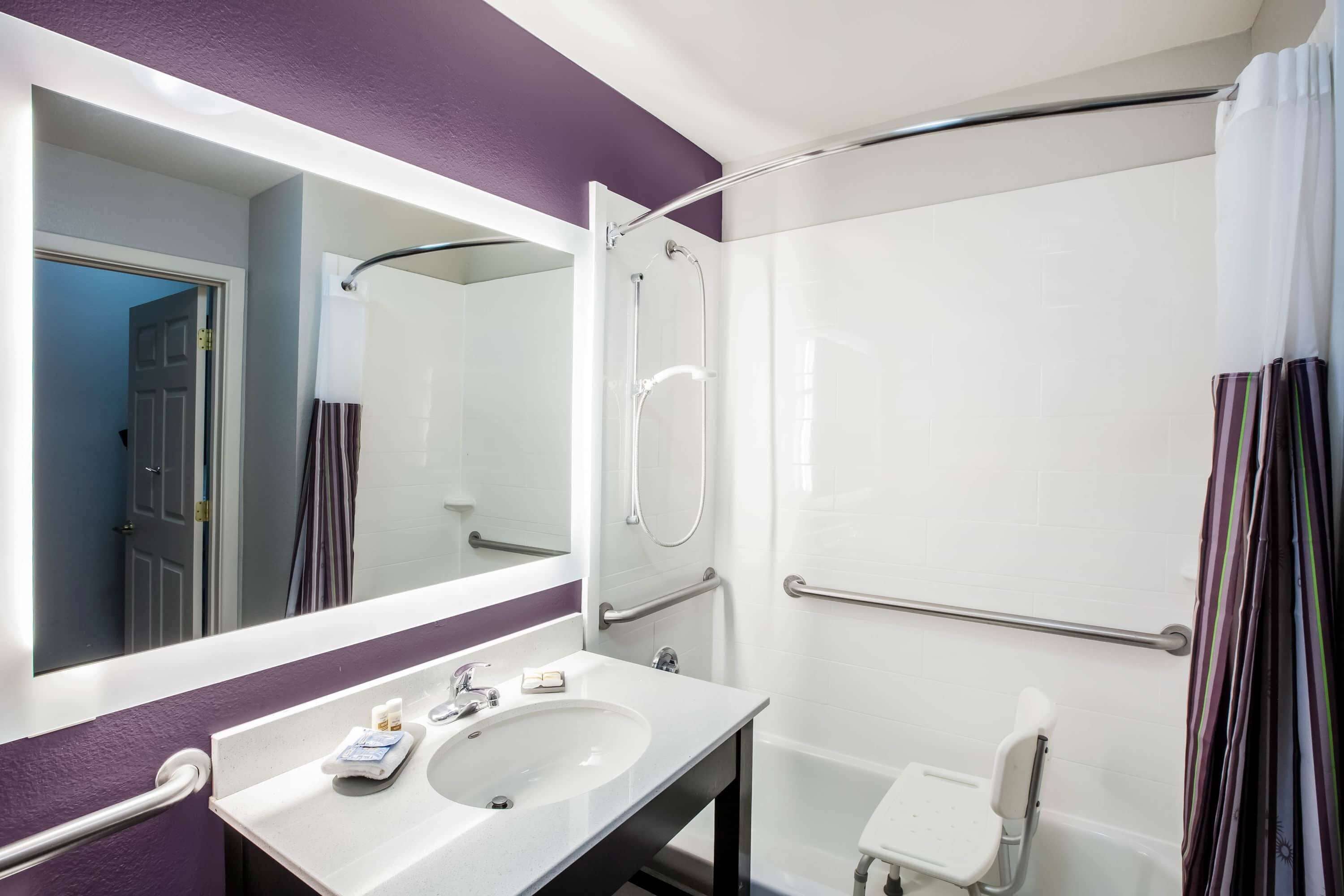 A bathroom with a white sink, a mirror, a shower with a glass door, and a white toilet.