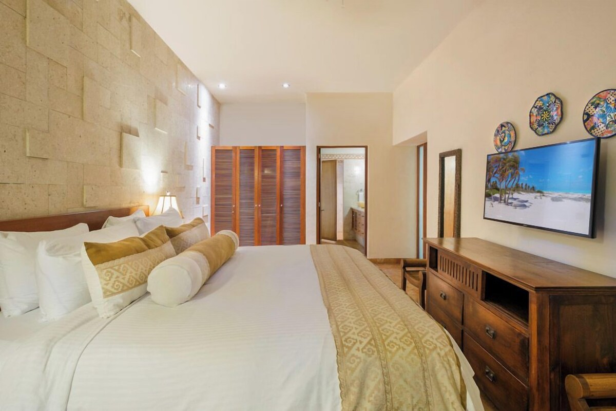 A hotel room with a large bed, wooden wardrobe, a television, and decorative plates on the wall.