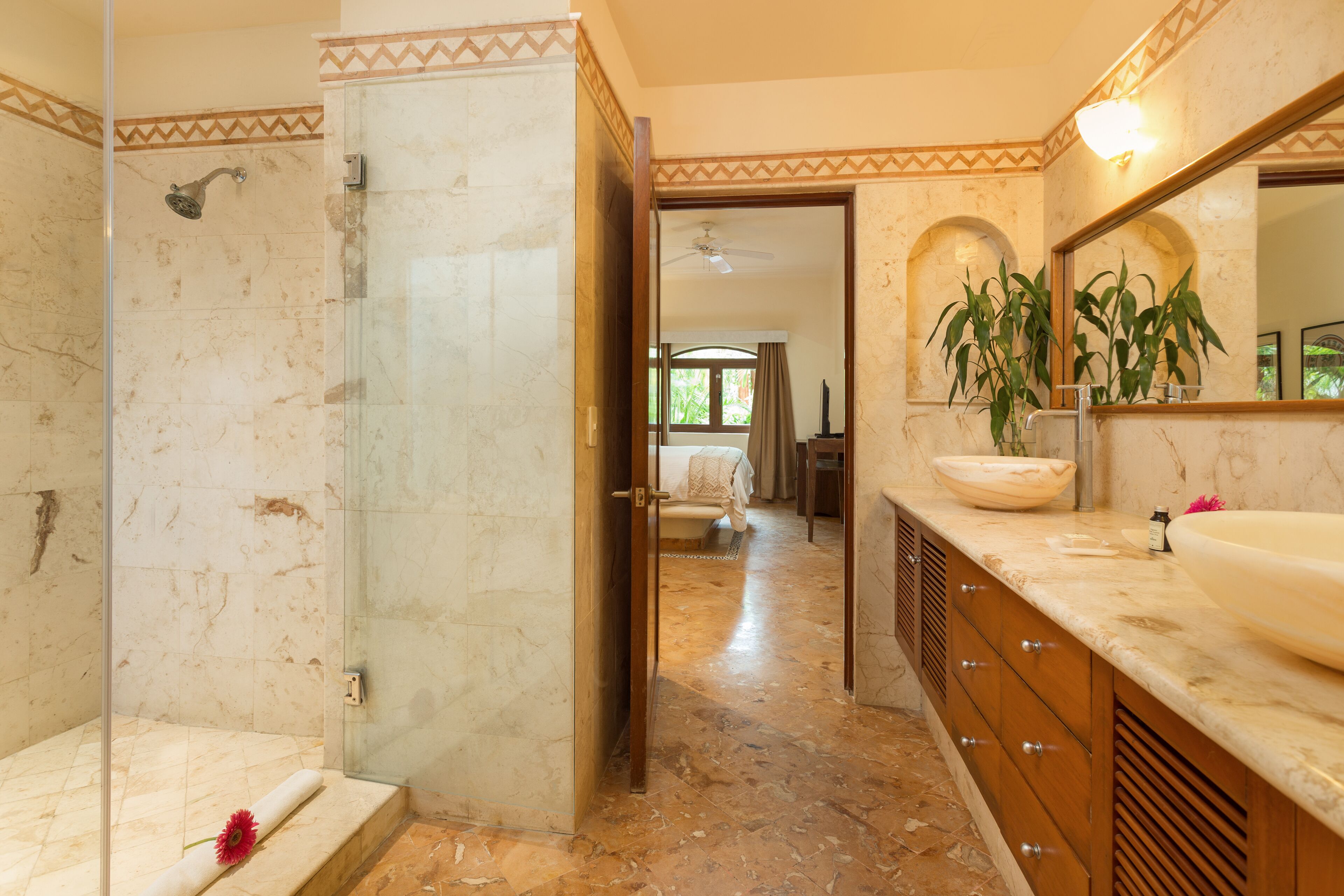 Un baño con cabina de ducha de vidrio, un espejo grande y un tocador con lavamanos y espejo.