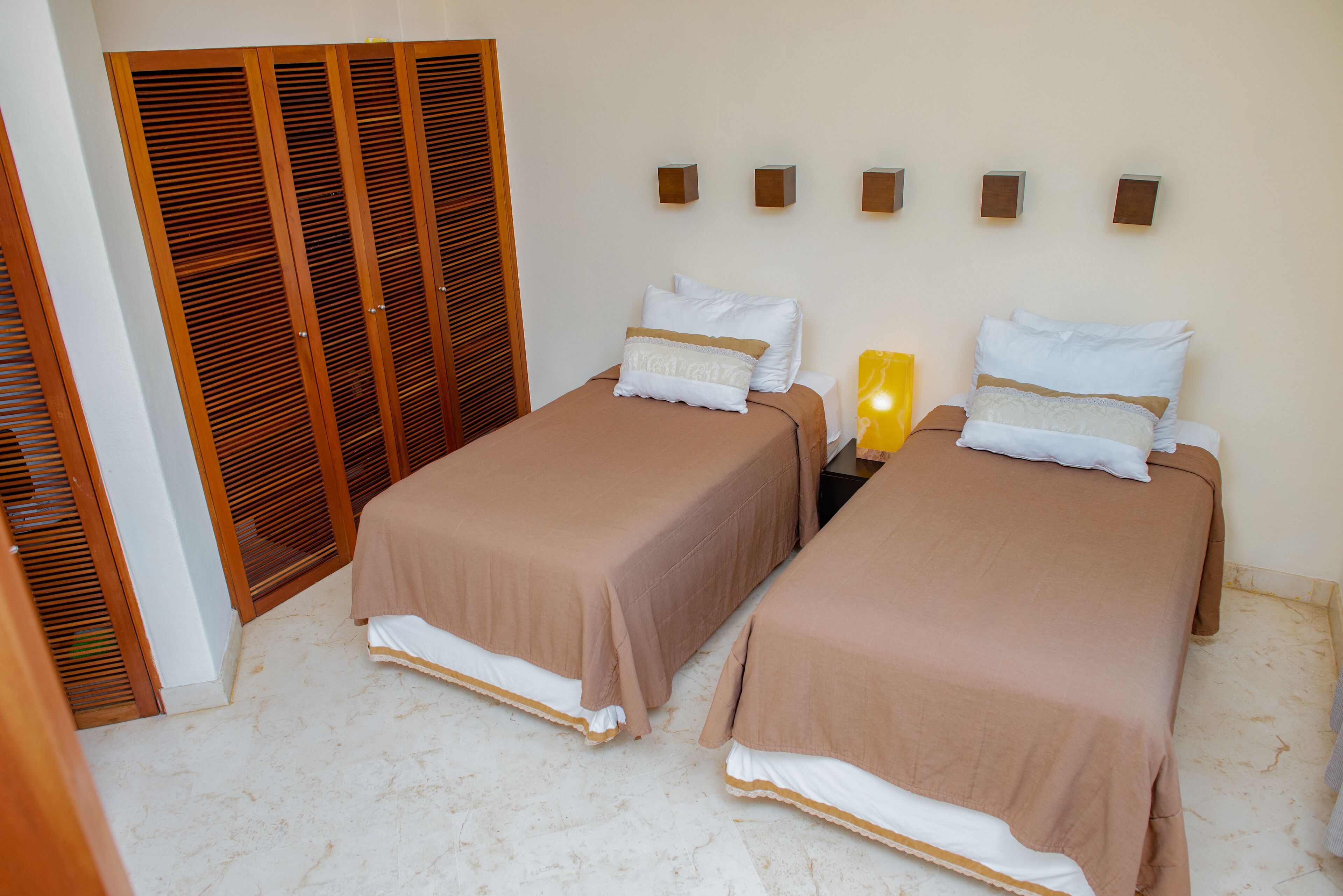 Een kamer met twee bedden, houten kasten en wandlampen.