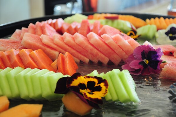 Diversa selección de frutas y verduras cortadas dispuestas en una bandeja.
