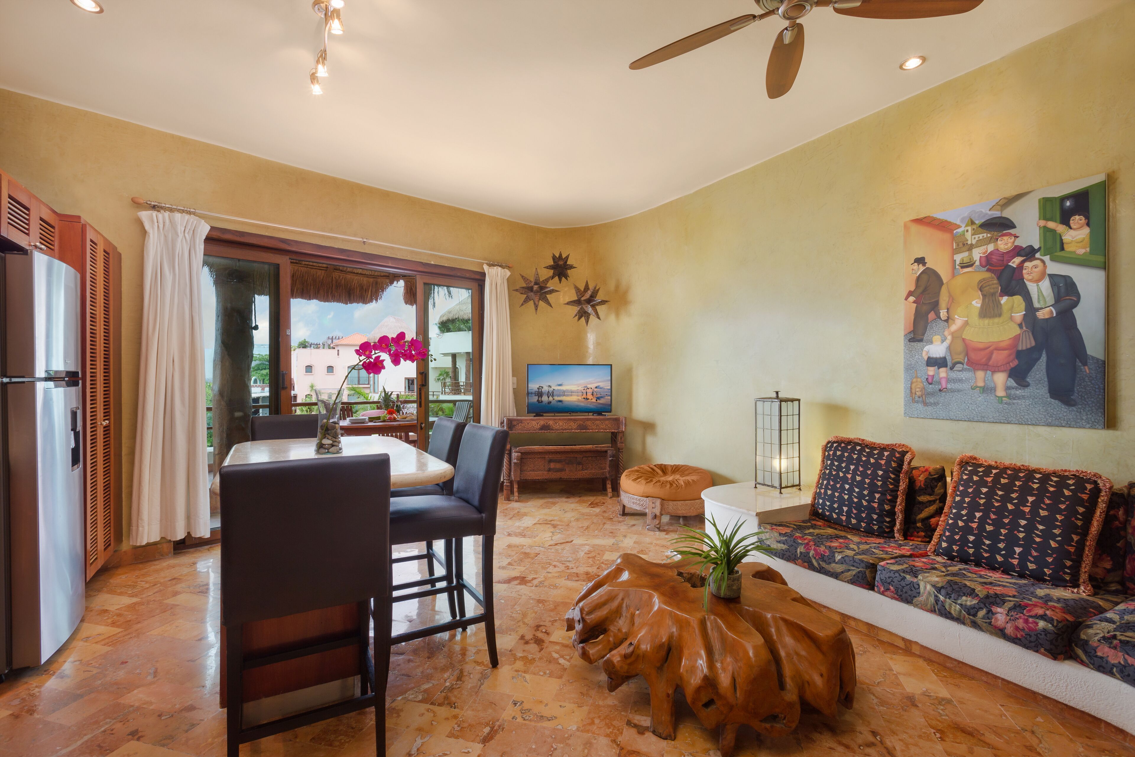 A living room with a dining area, a sofa, a TV, and a ceiling fan.