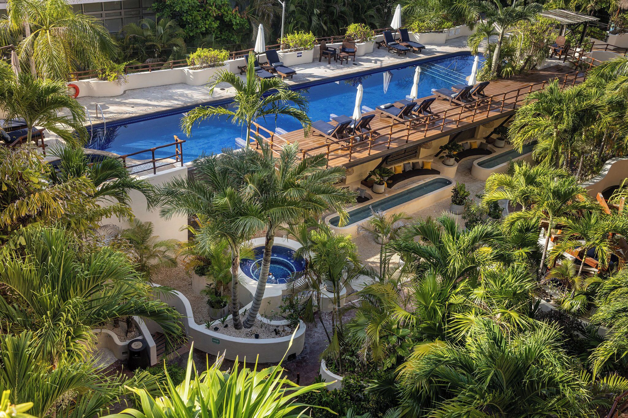 A pool area with multiple lounge chairs and a hot tub.