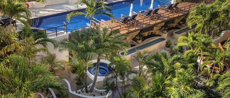 A pool area with multiple lounge chairs and a hot tub.