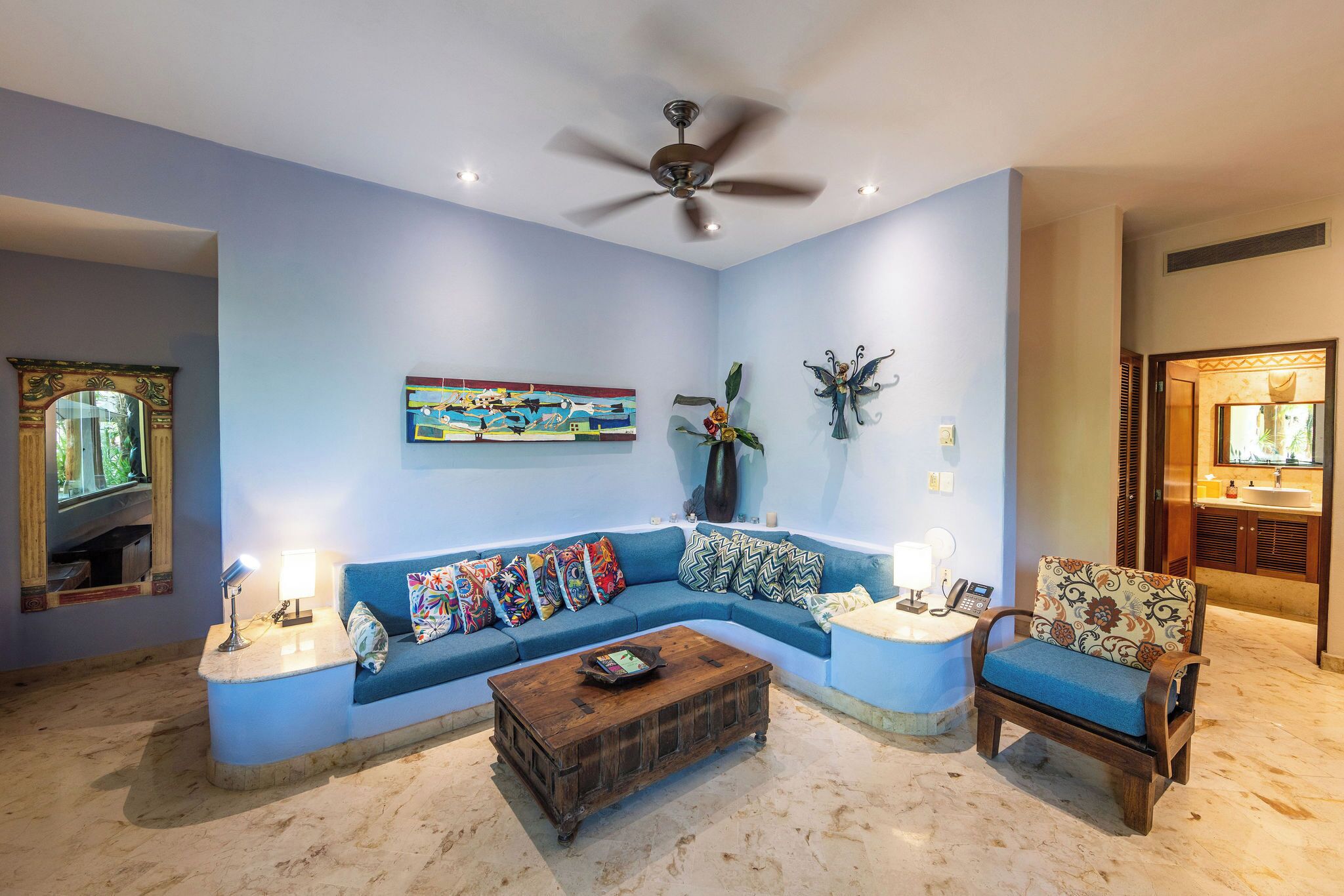 A living room with a blue sofa, a wooden coffee table, and a ceiling fan.