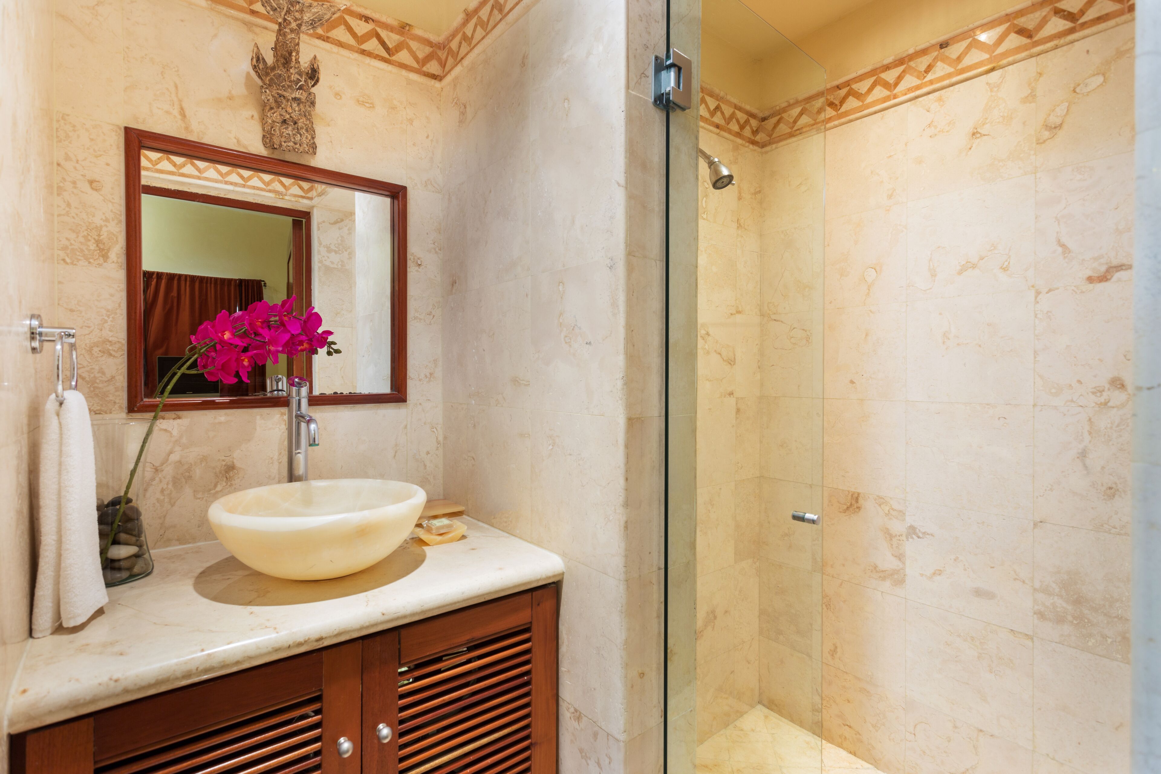 A bathroom with a large mirror, a sink, and a shower.