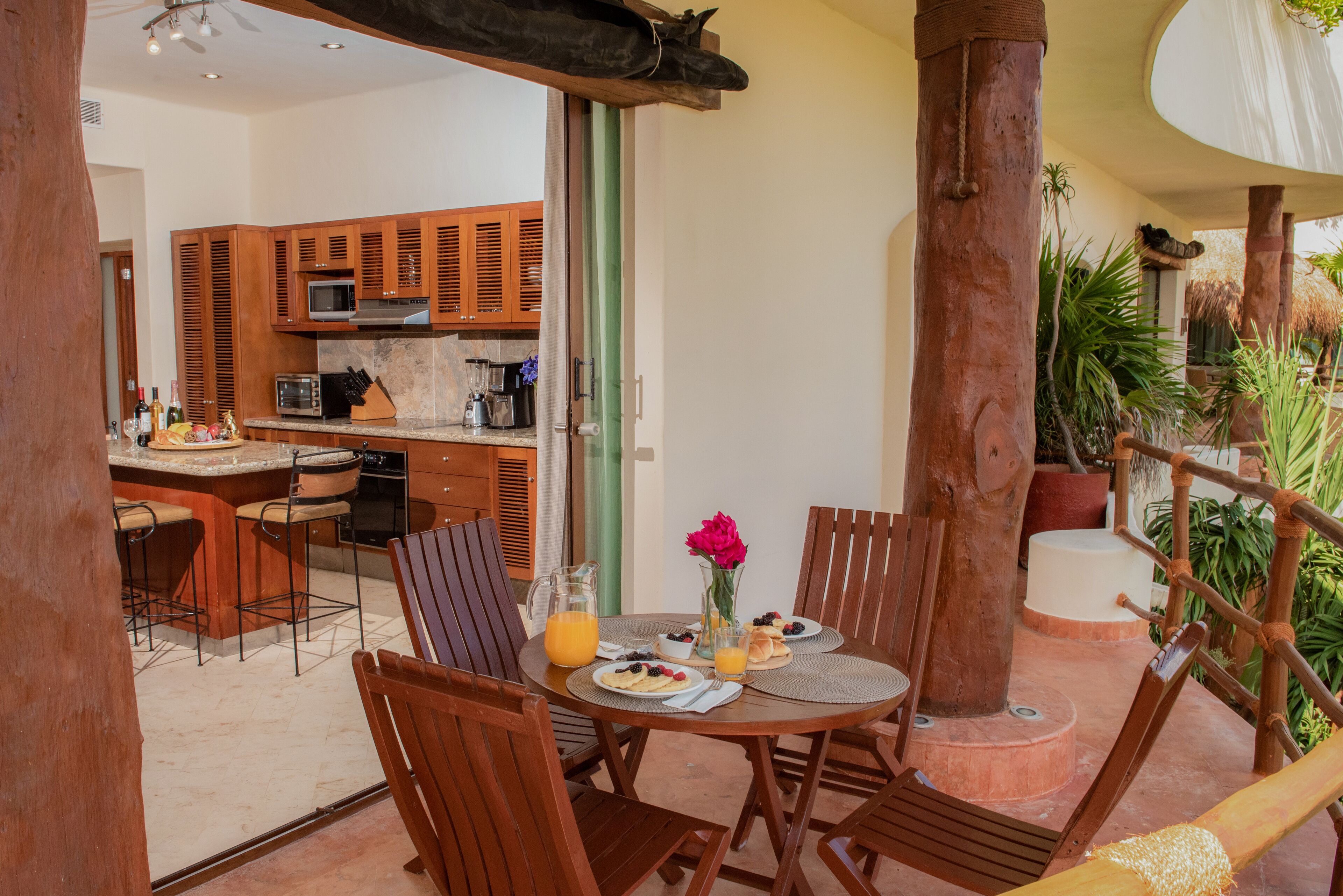 A dining area with a table set for breakfast, wooden chairs, and a view of the kitchen.