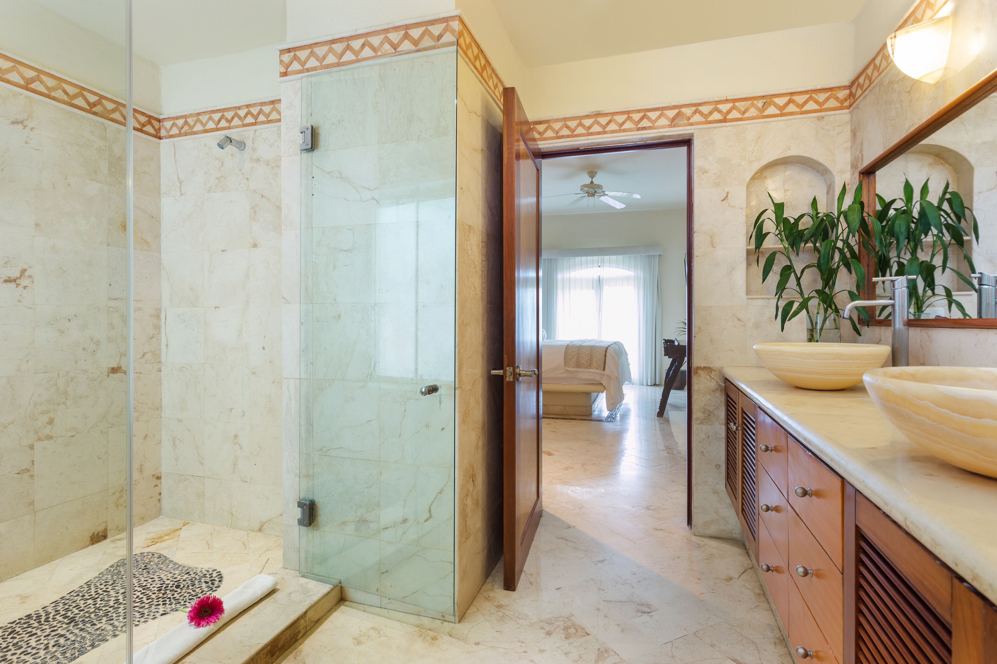 Un baño con cabina de ducha de vidrio, tocador con lavamanos grande y espejo sobre el lavamanos.