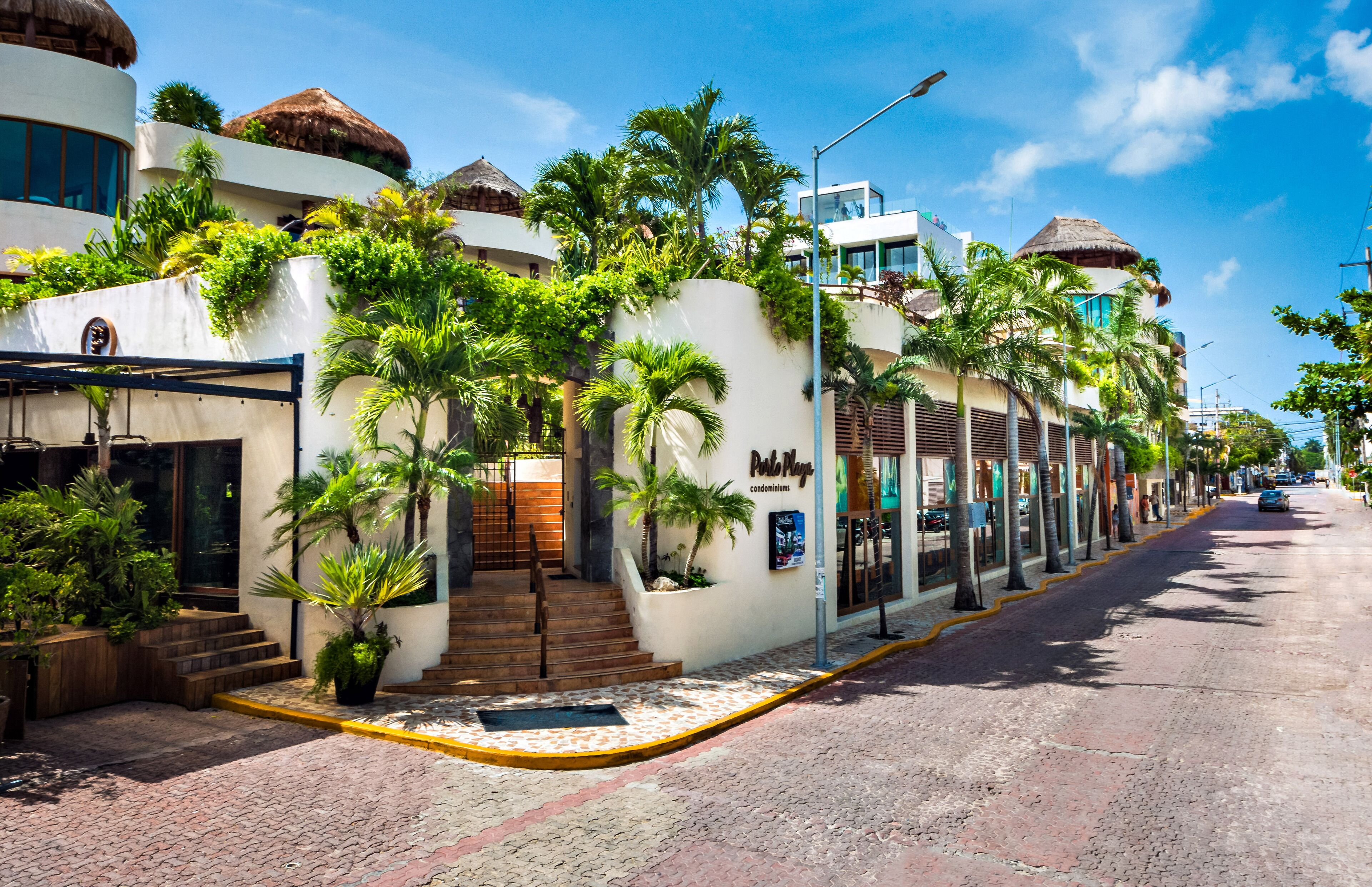 A hotel with a tropical theme, featuring palm trees and thatched roofs.