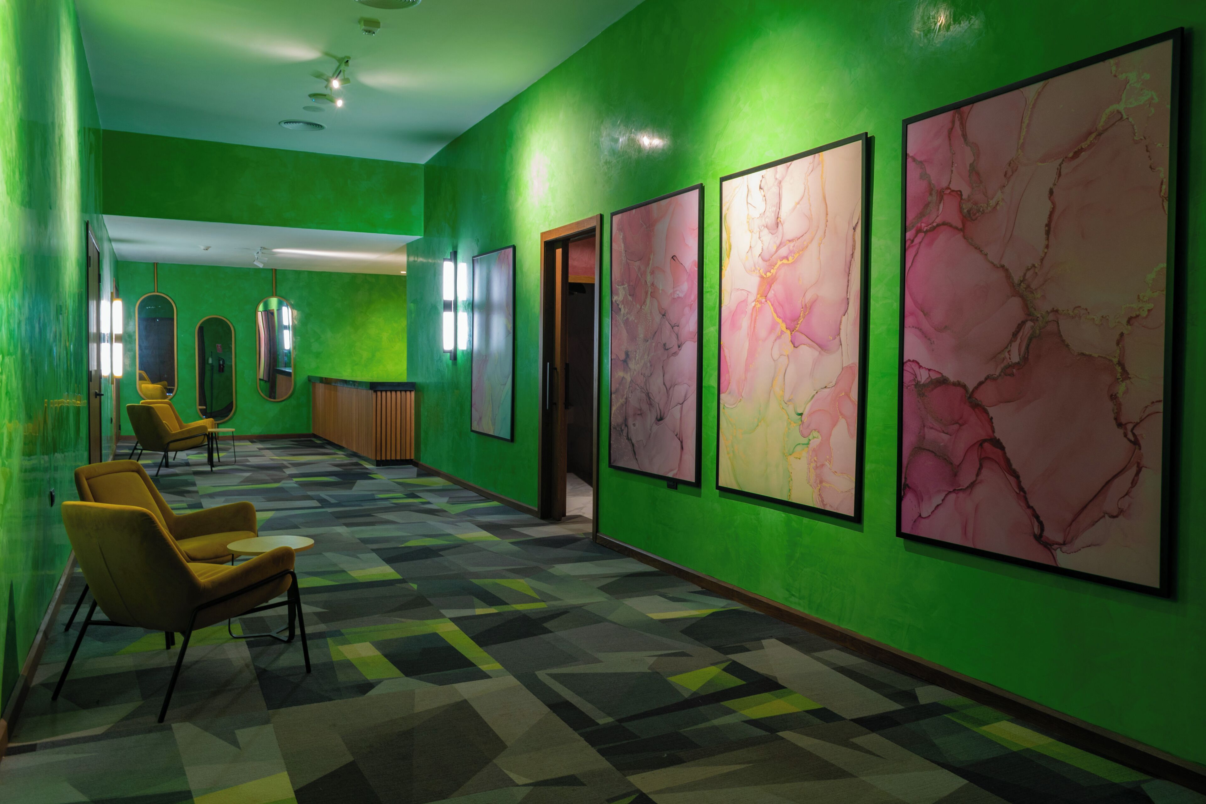 A hallway with green walls, marble artwork, and modern seating.