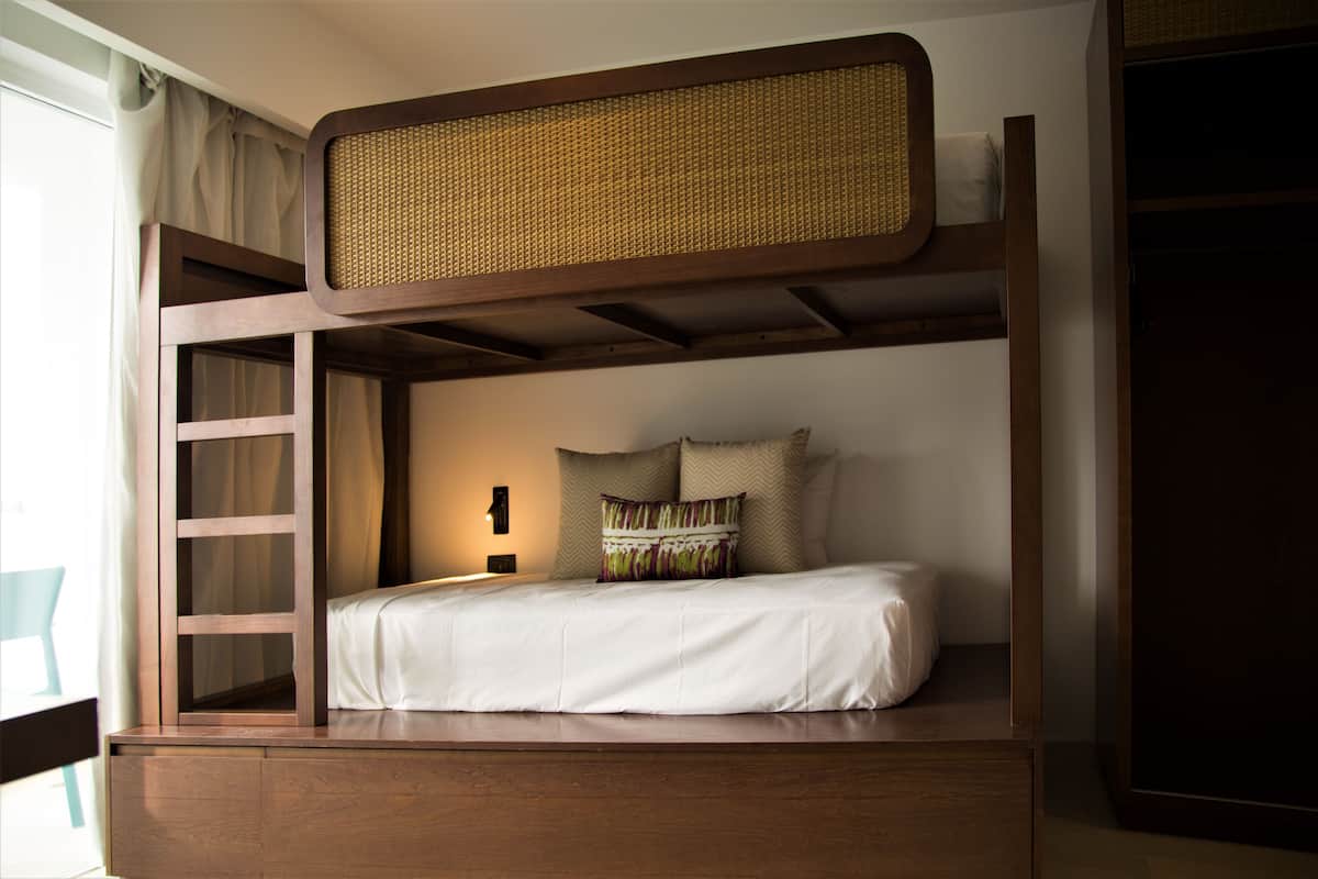 Una cama litera con estructura de madera y cabecero tejido.
