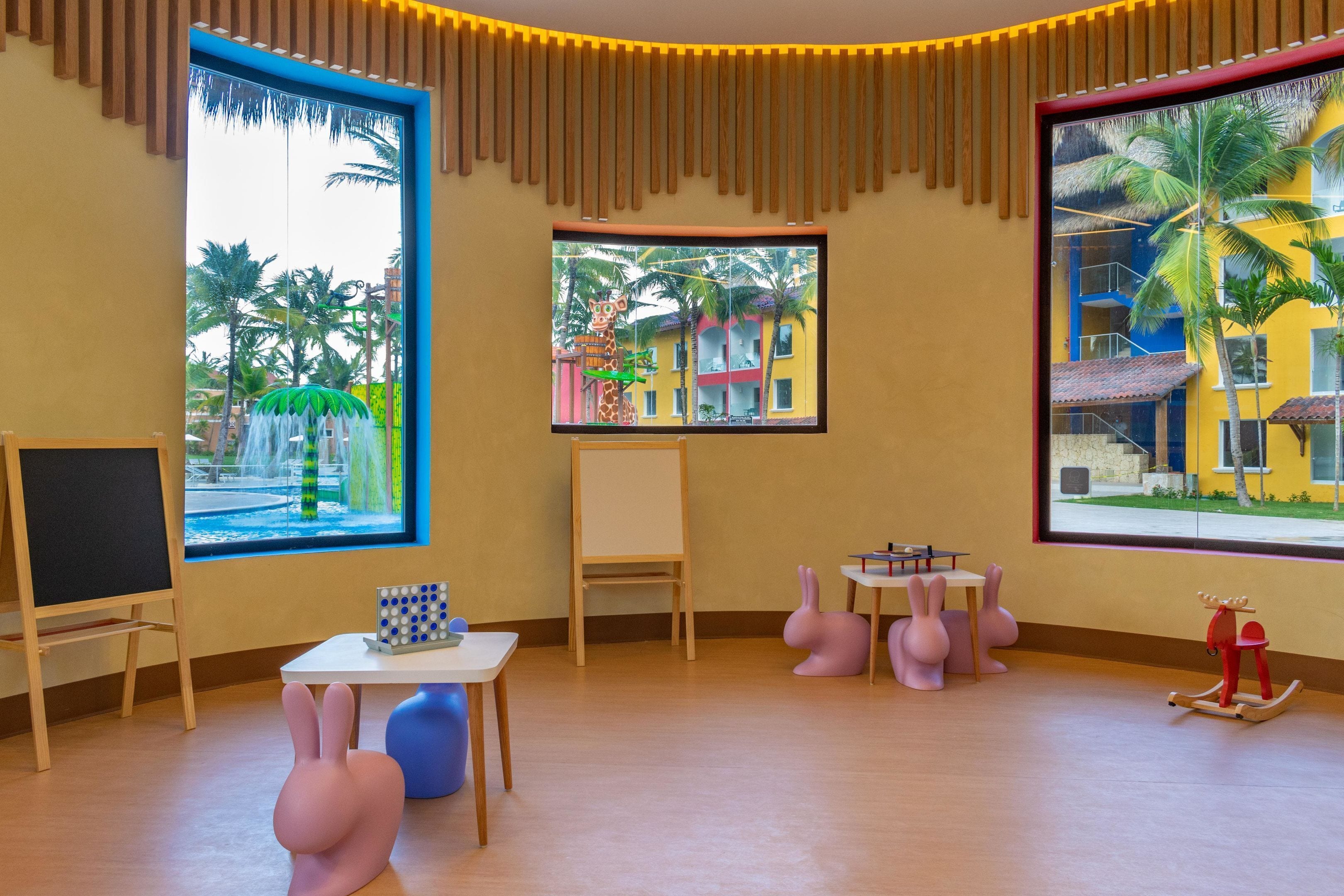 A room with large windows, a whiteboard, a table with a puzzle, and a rocking horse.