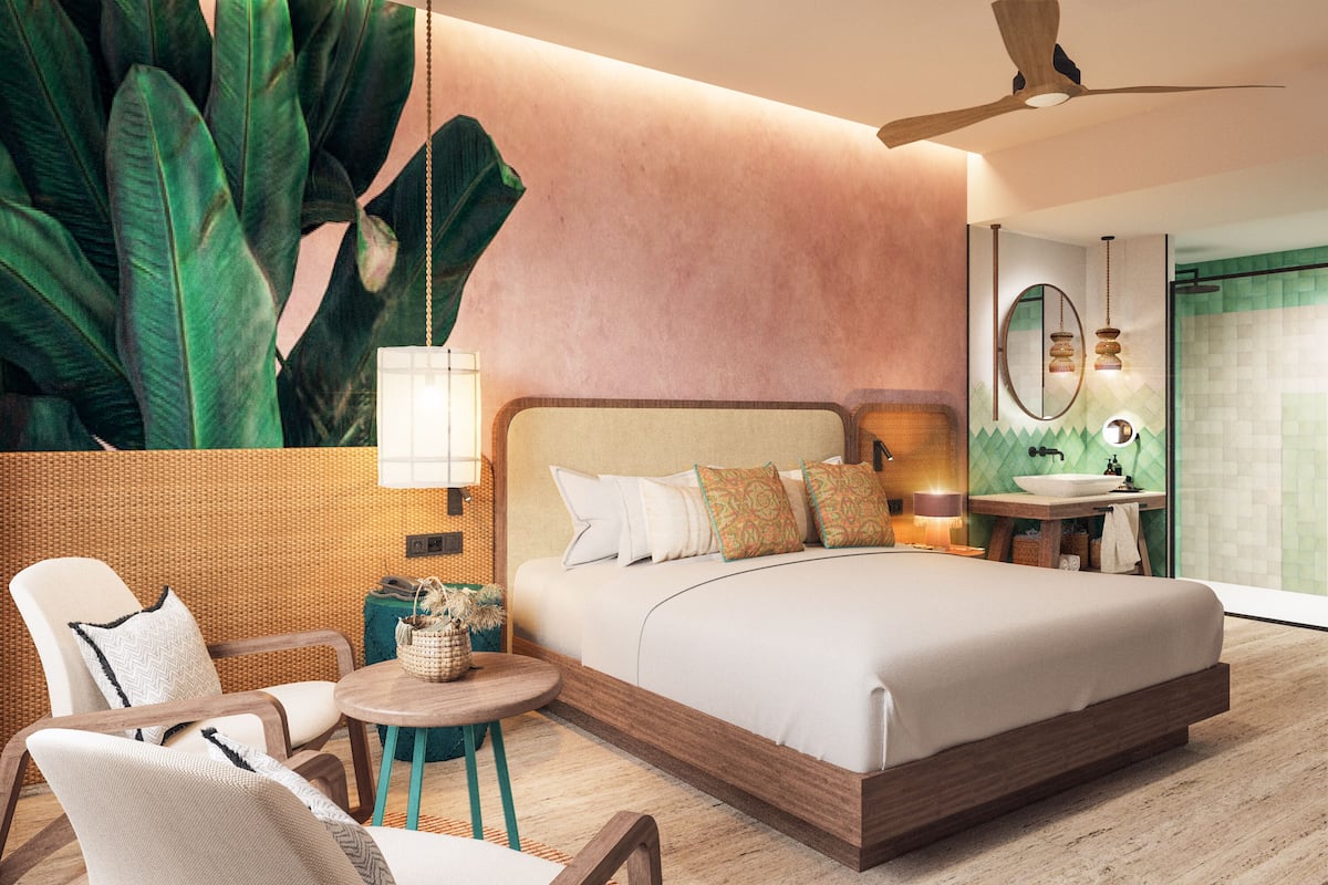 Un dormitorio moderno con una cama grande, un rincón de estar con sillas, una mesita redonda pequeña y una planta de gran tamaño.