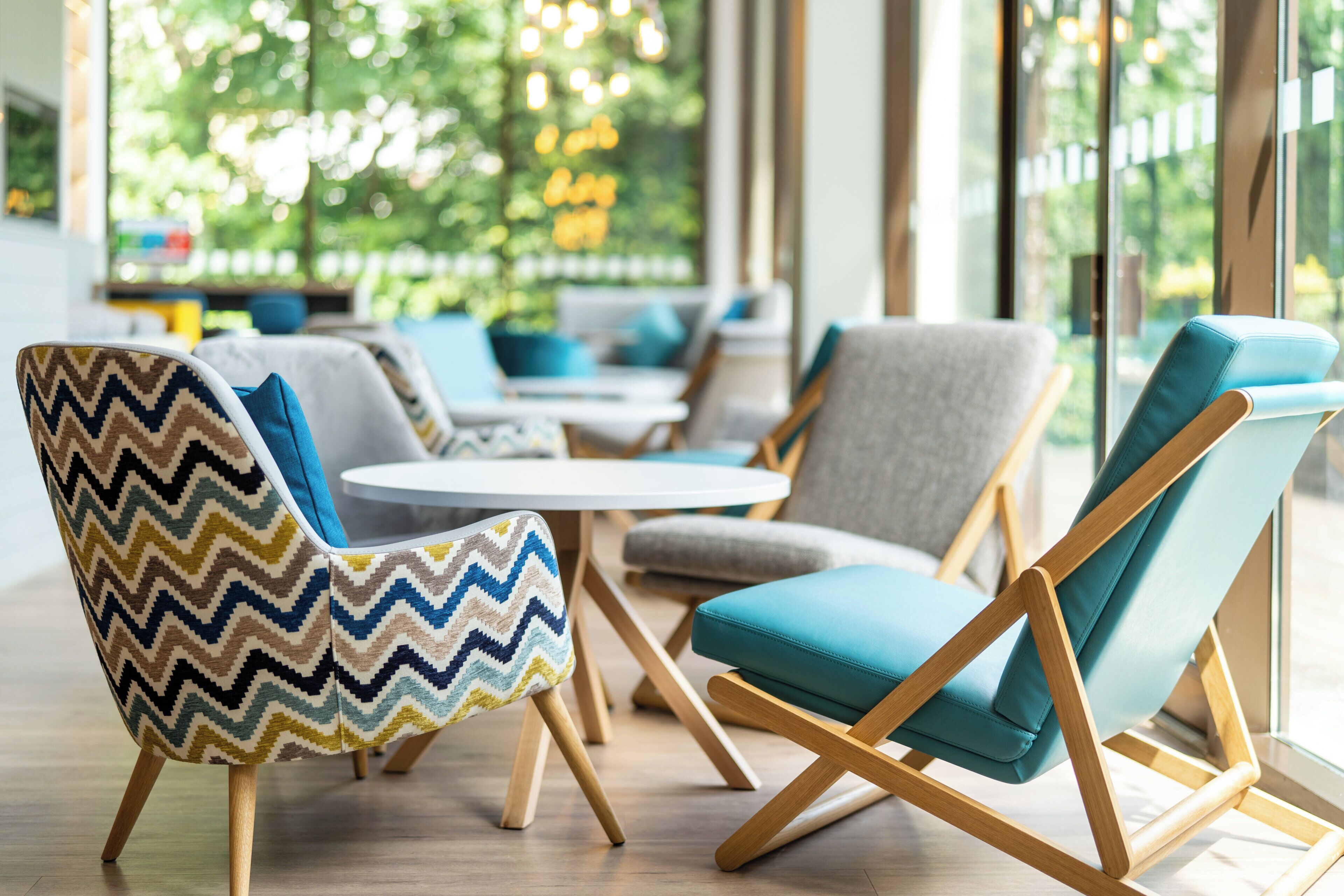 A modern lounge area with seating arrangements, including a patterned armchair and a blue cushioned chair.