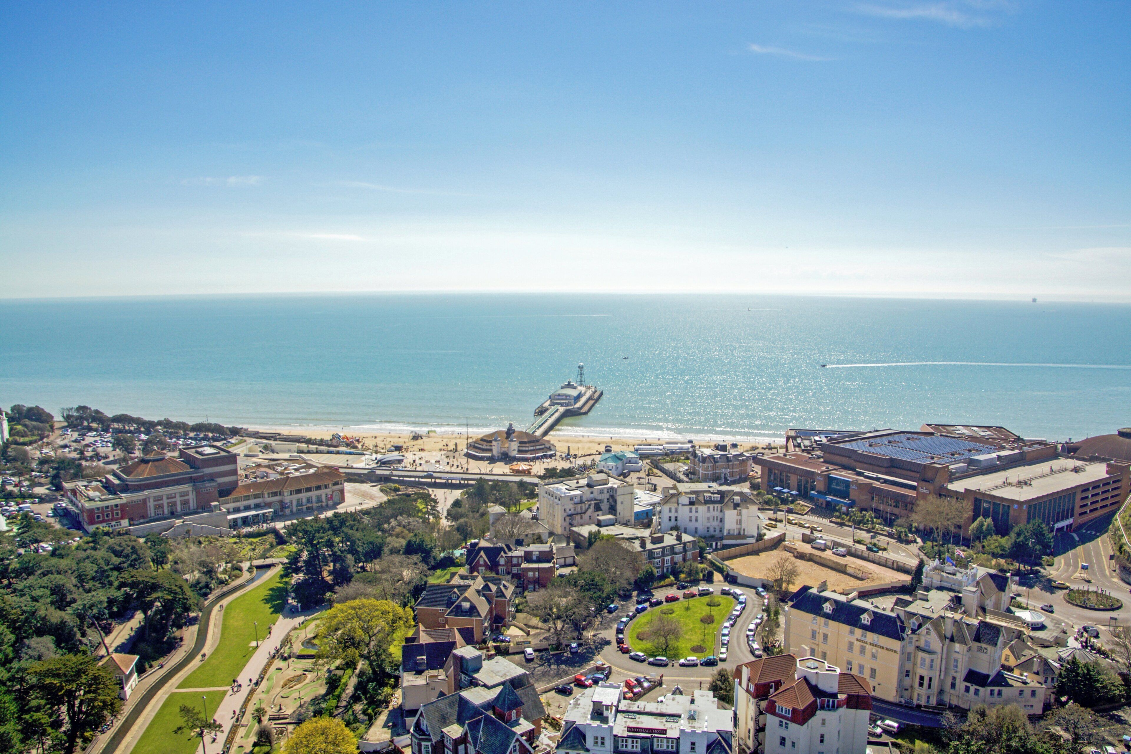 A coastal town with a marina, a beach, and a variety of buildings including a hotel.