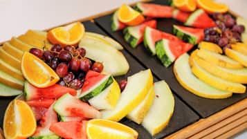 En bakke med et udvalg af frugter, herunder vandmelon, appelsiner og druer.