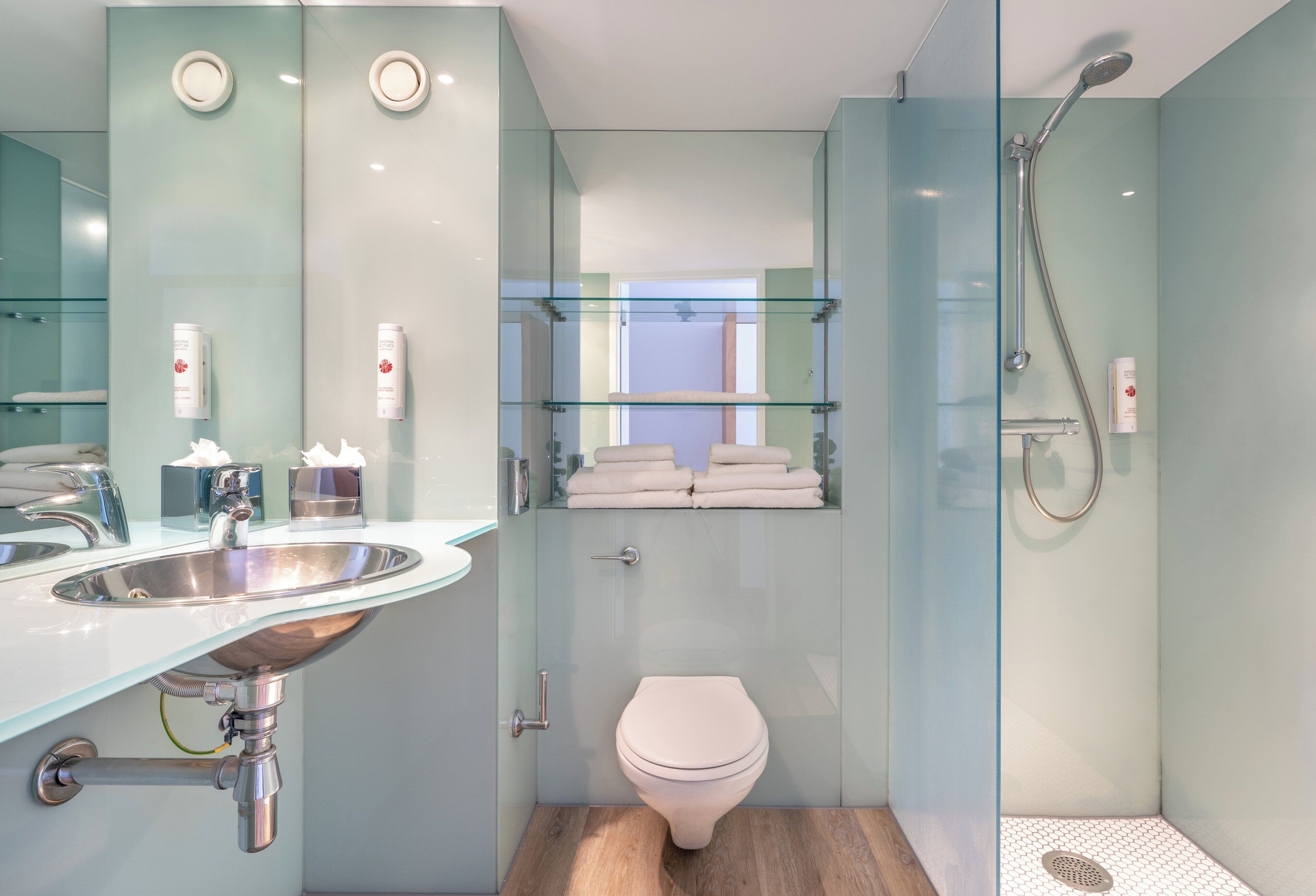 Un baño moderno con cabina de ducha de vidrio, inodoro y lavabo con espejo.