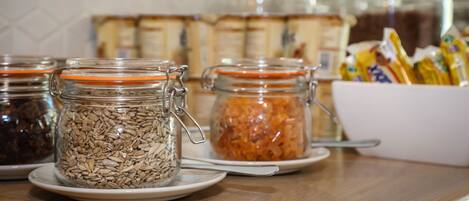A breakfast buffet with various food items in glass jars and a white bowl with packaged goods.