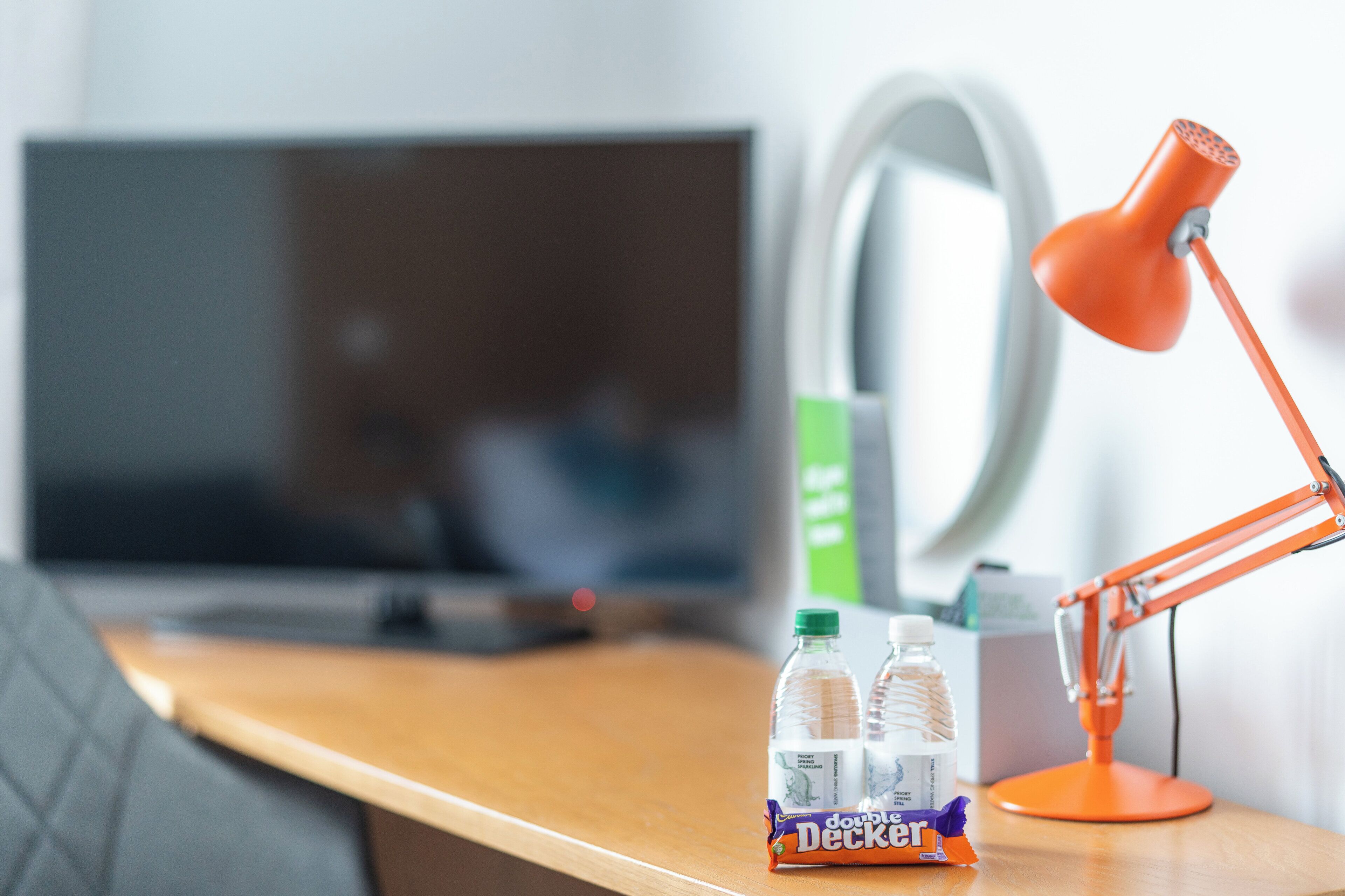 A desk with a laptop, a desk lamp, and two bottles of water.