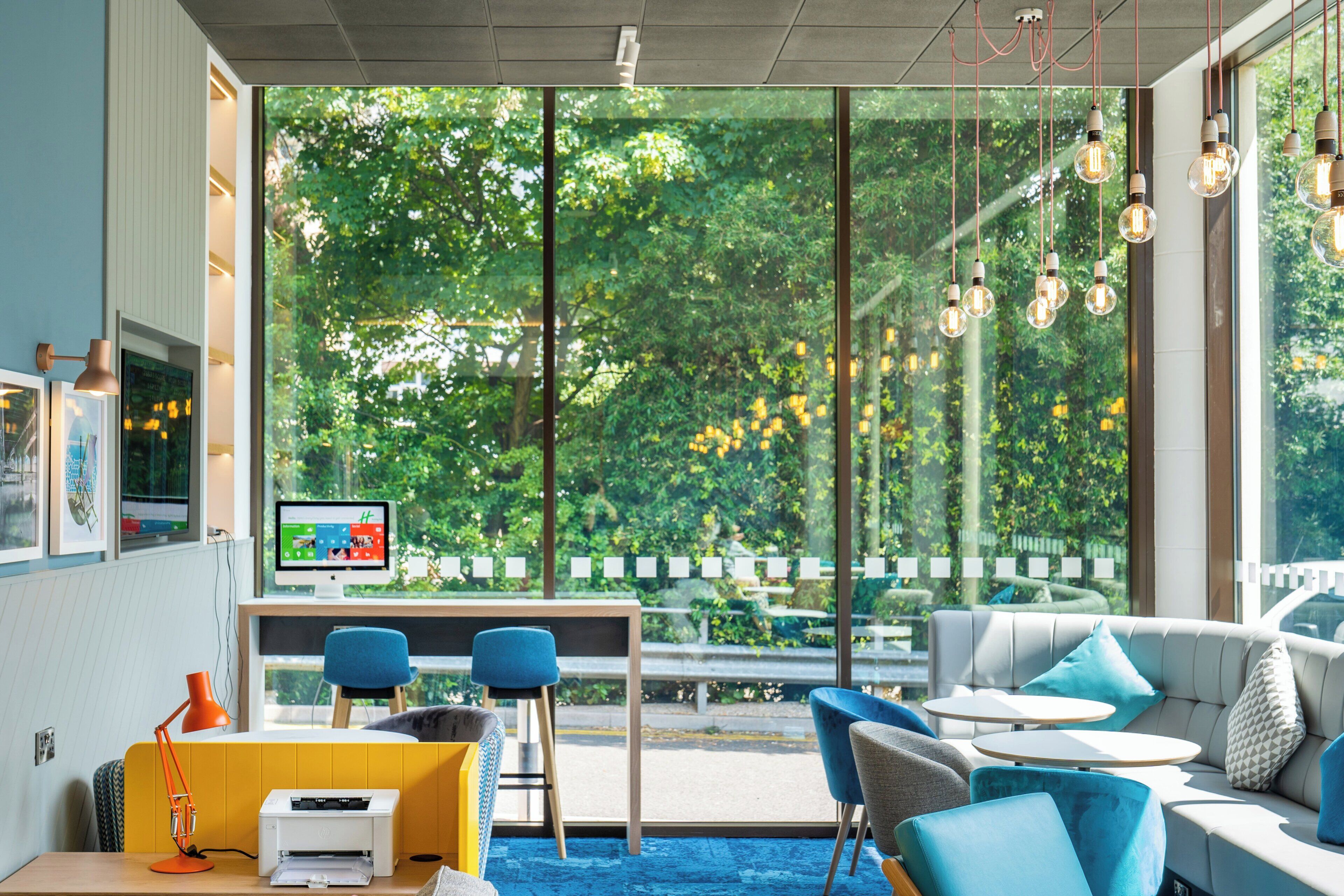 Una sala de estar moderna con un ventanal grande, un escritorio con computadora y una zona de estar.