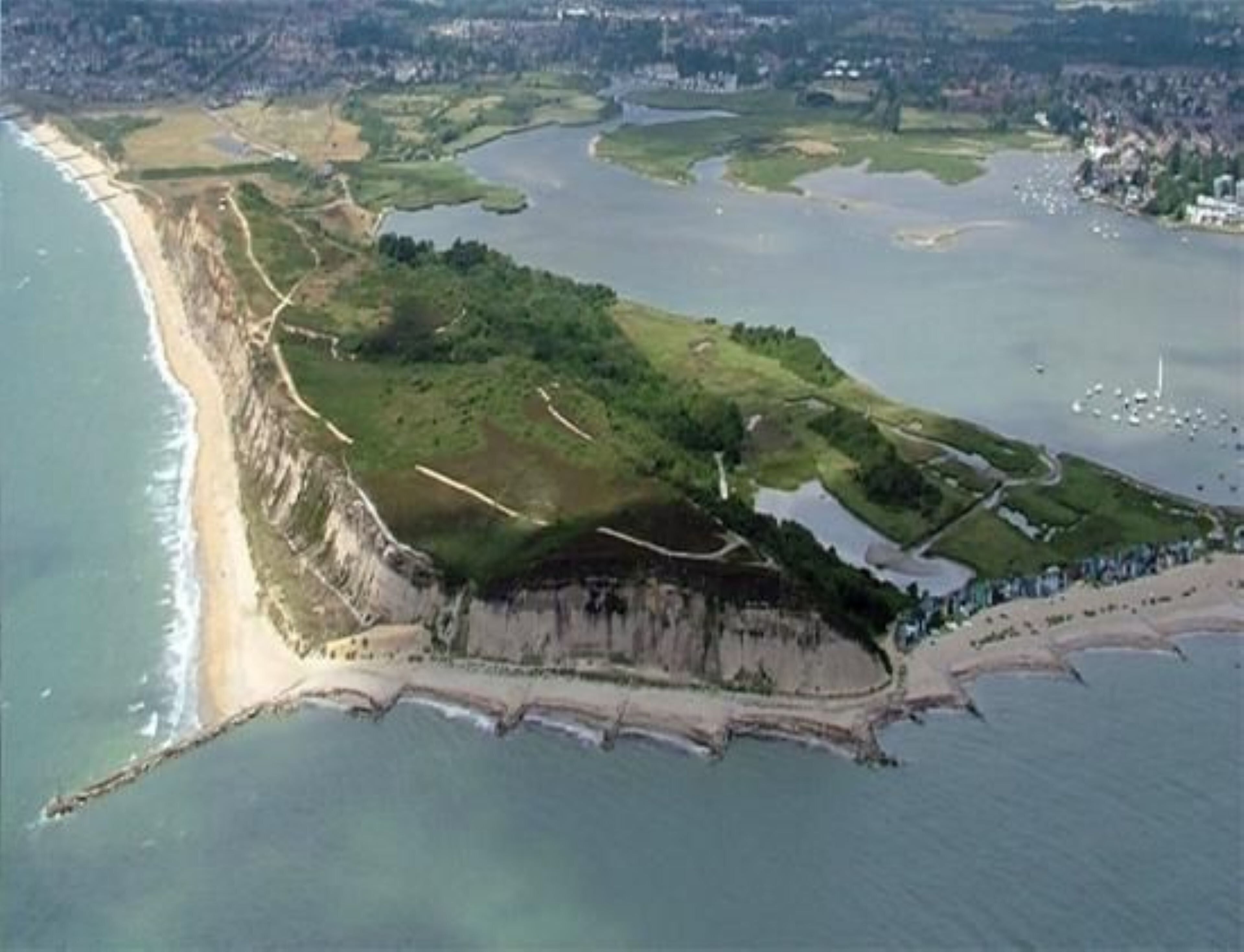 An aerial view of a coastal area with a beach, cliffs, and a water body.