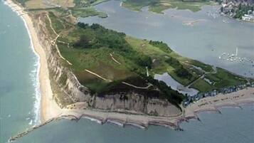 An aerial view of a coastal area with a beach, cliffs, and a water body.