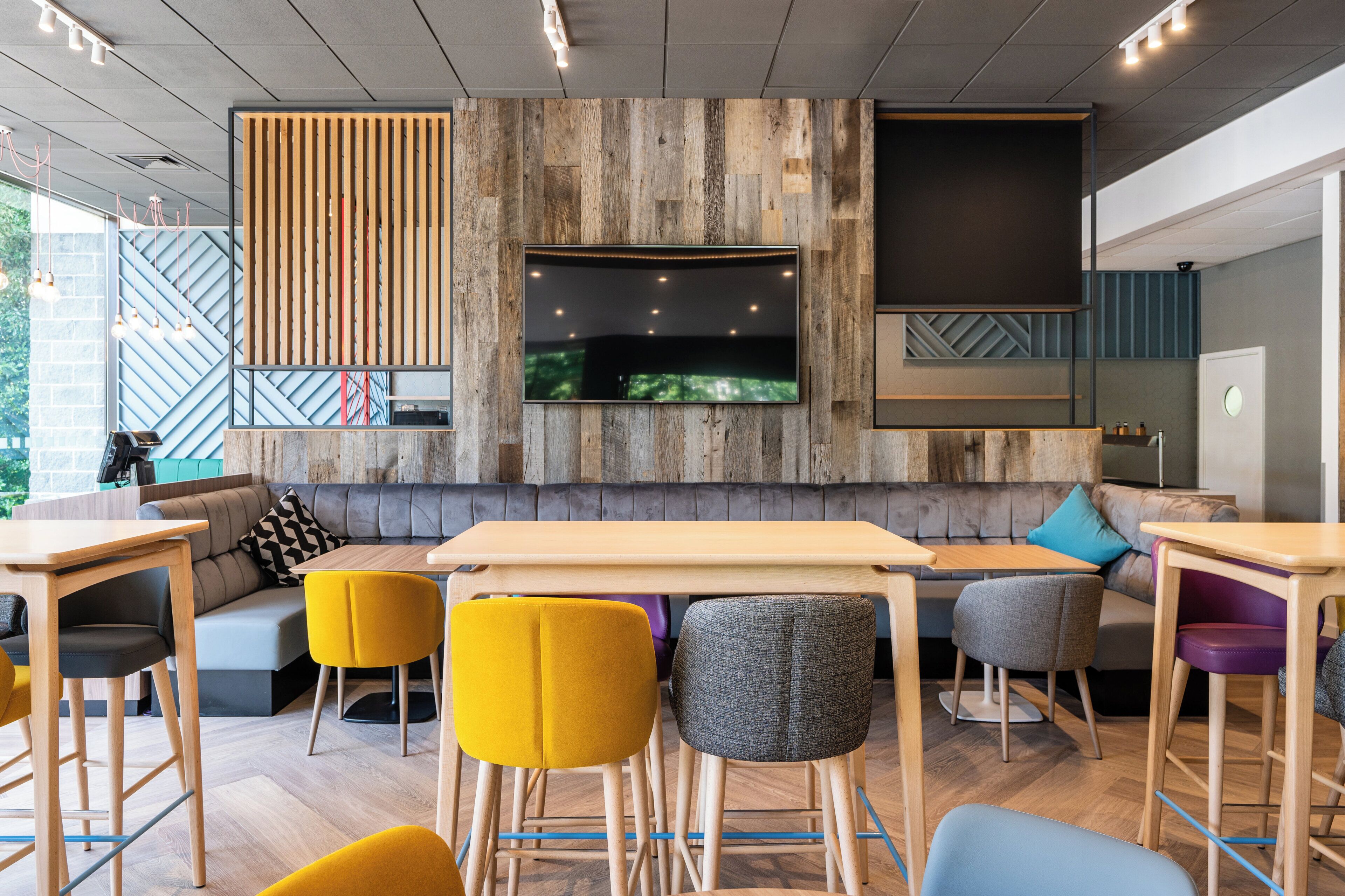 A modern interior with a wooden wall panel, a flat-screen TV, and a seating area with a sofa and chairs.