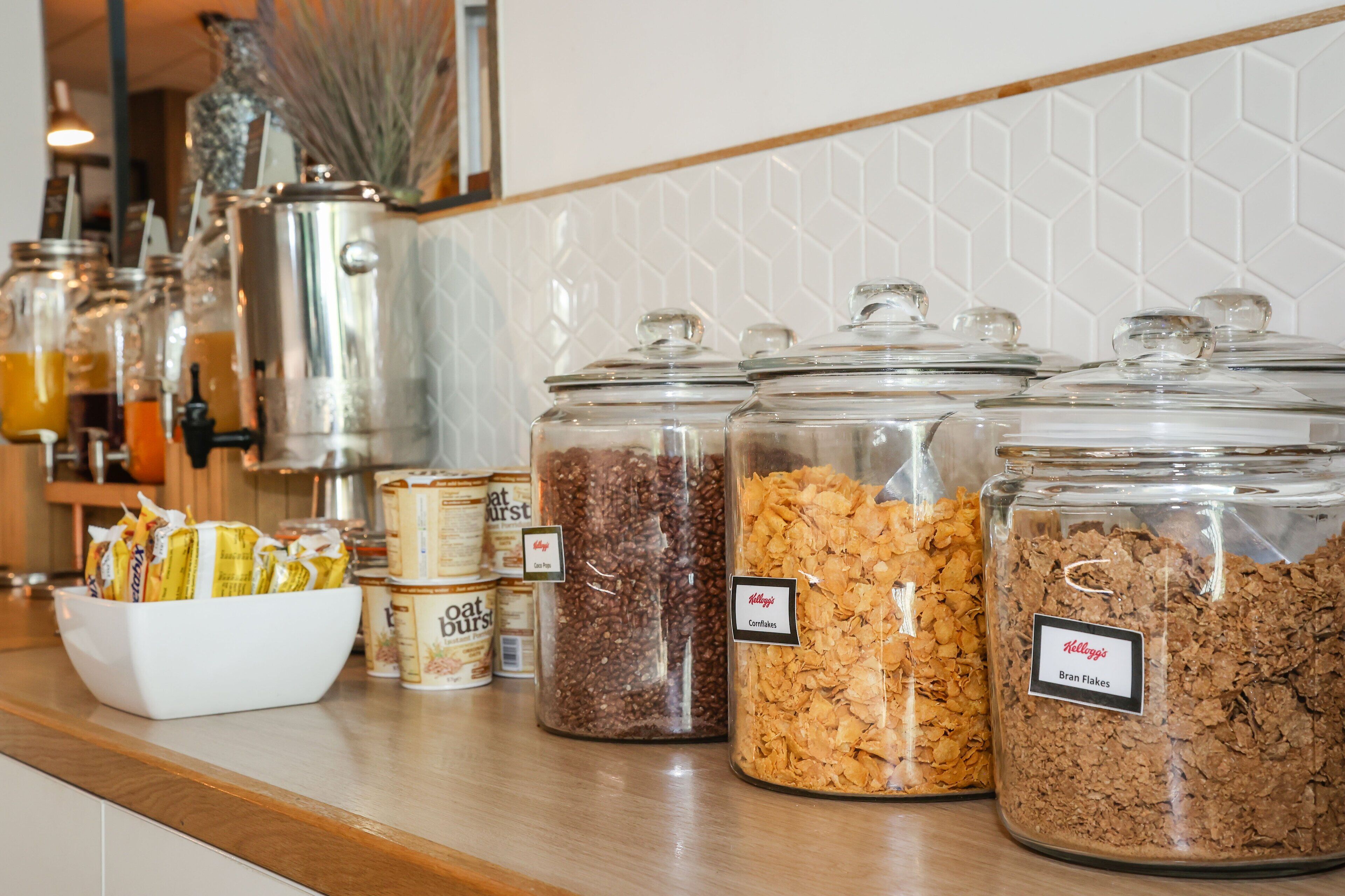 Una encimera de cocina con diferentes alimentos en recipientes de vidrio, como cereales y aperitivos.