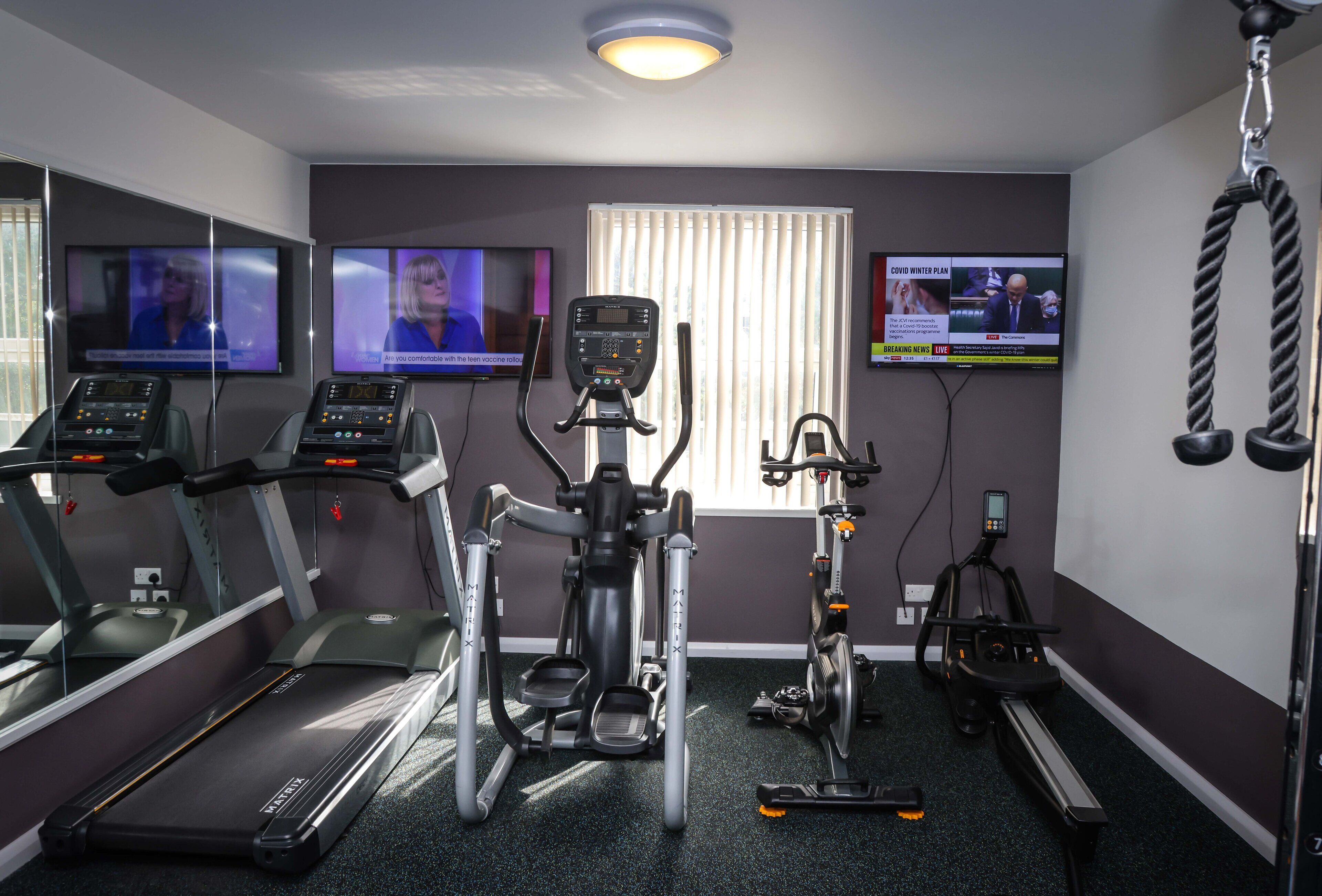 Un gimnasio con cintas de correr, elípticas y una bicicleta estática.