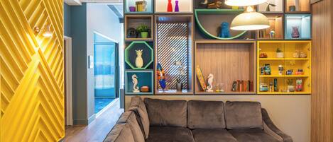 A modern interior with a sectional sofa, a round table, and a variety of decorative items on shelves.